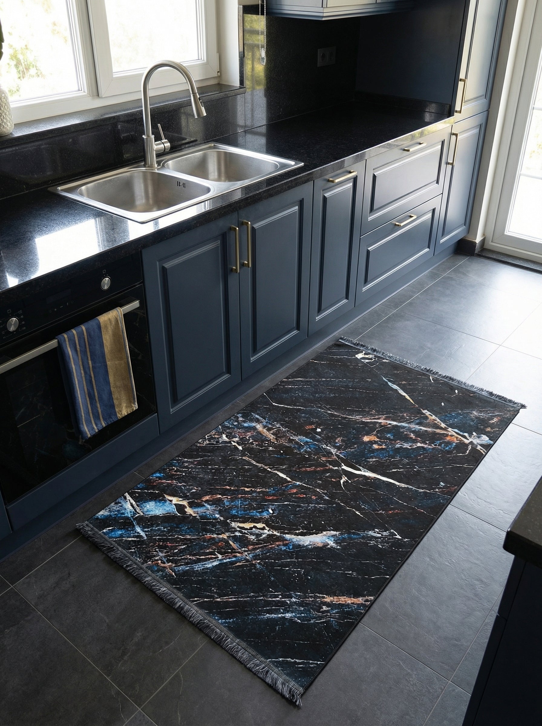Tapis rectangulaire noir à franges courtes, motifs marbrés abstraits bleus, dorés et blancs, dans une cuisine