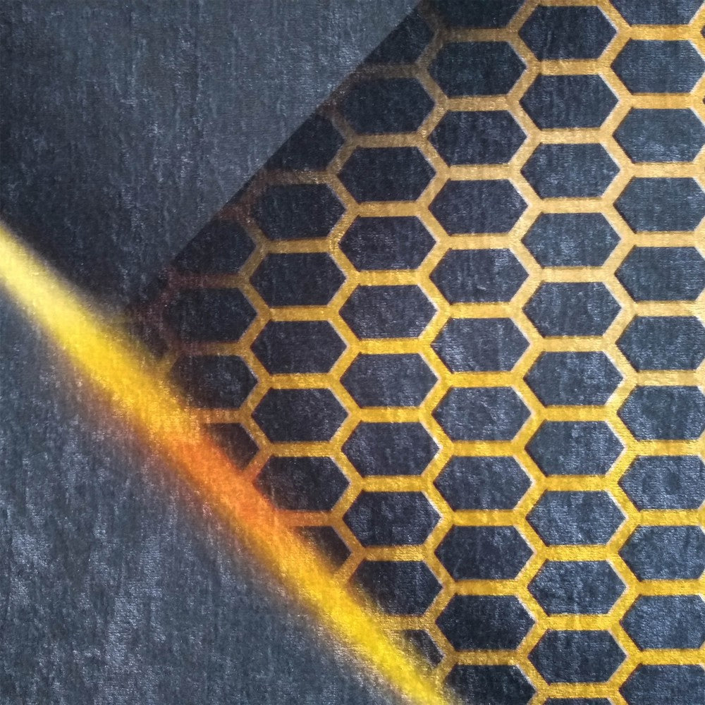 Tapis gris foncé avec des motifs hexagonaux dorés, traversé d'une bande lumineuse diagonale jaune et orangée