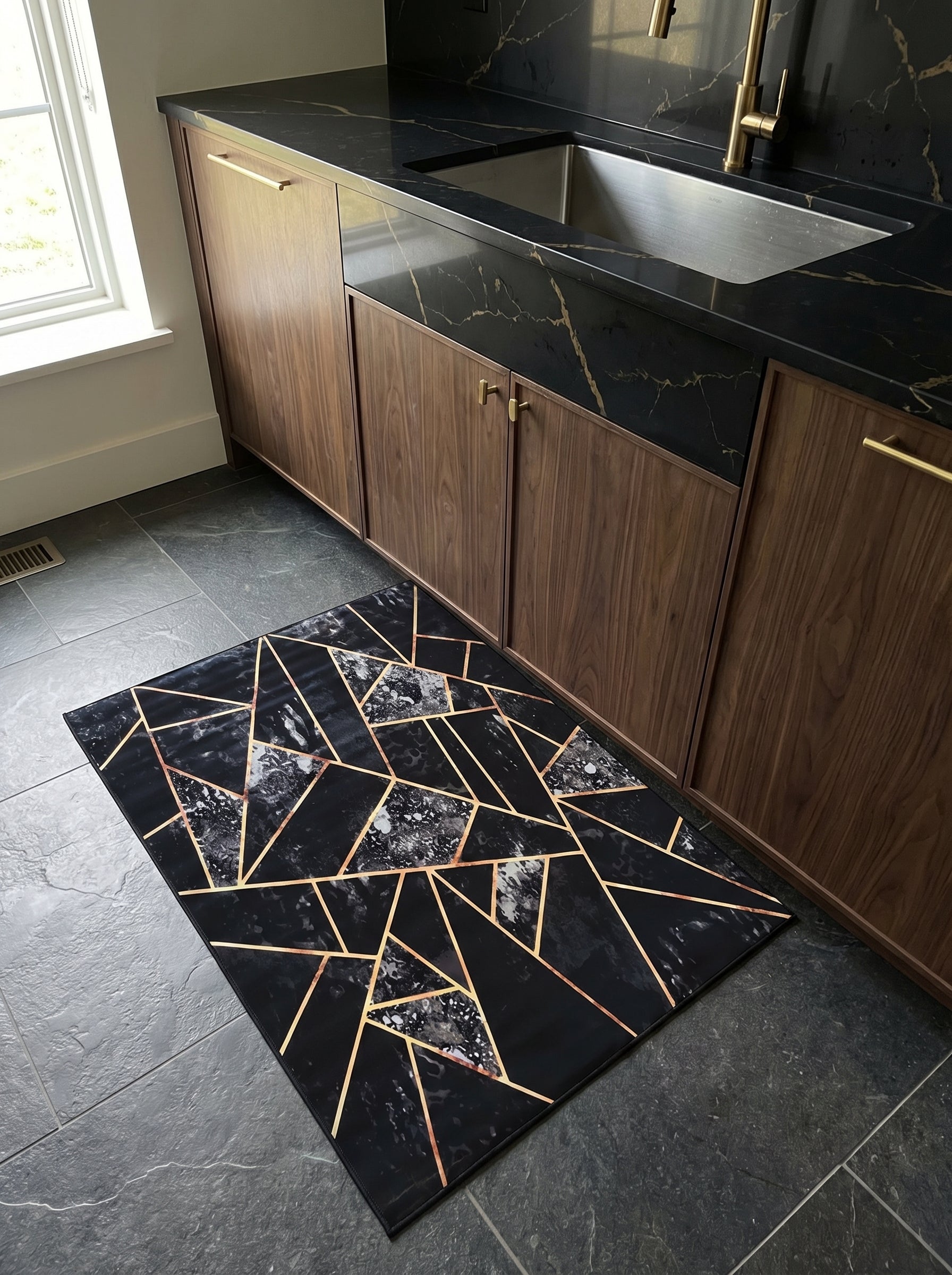Tapis rectangulaire noir à motifs géométriques marbrés blancs et lignes dorées, sur sol carrelé dans une cuisine