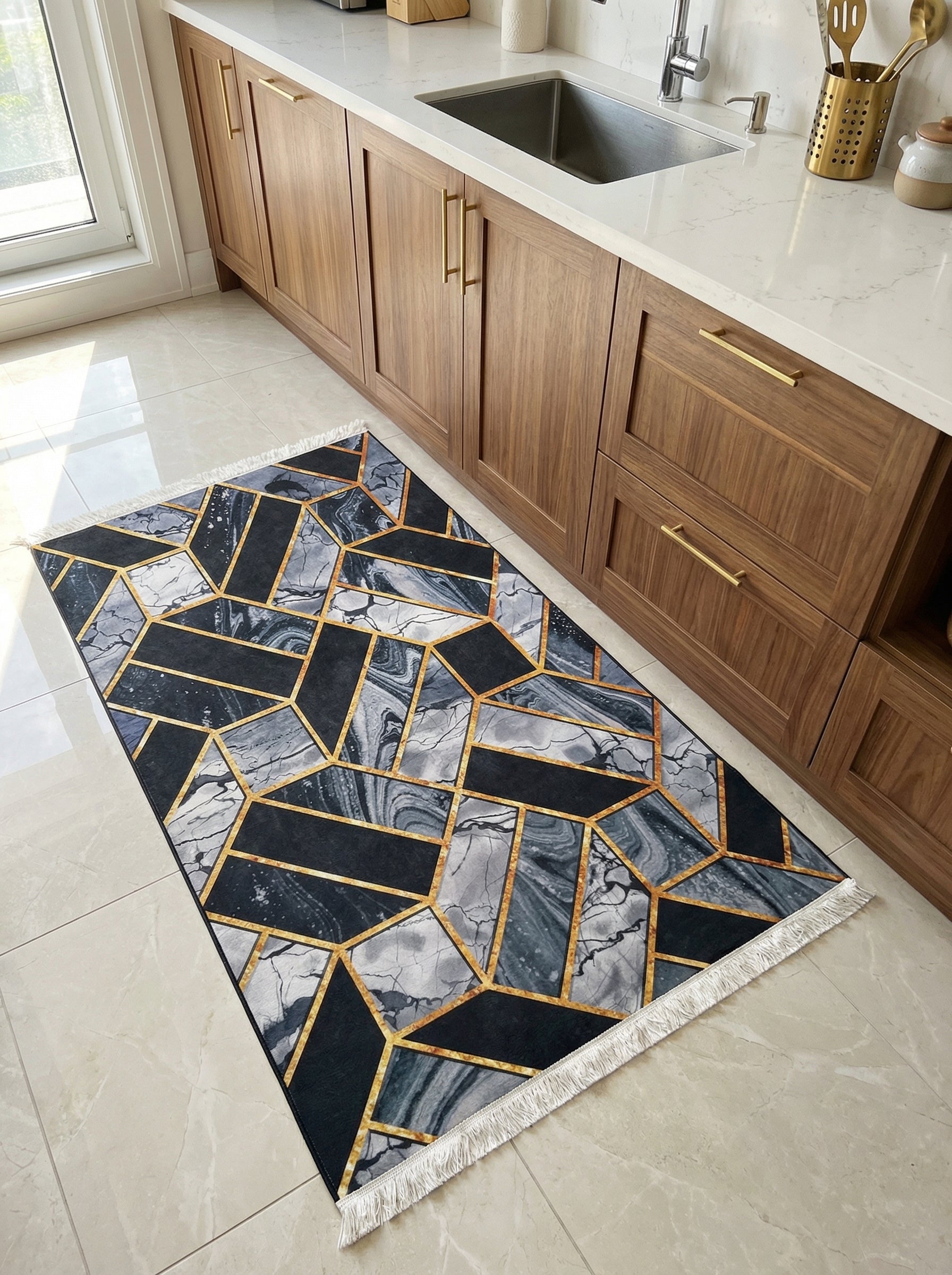 Tapis rectangulaire à motifs géométriques noir, gris marbré et lignes or, franges blanches, sur carrelage clair d'une cuisine