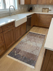 Tapis de couloir tissé beige, marron et gris dégradé avec des motifs géométriques en losanges et lignes dorées, sur le sol d'une cuisine