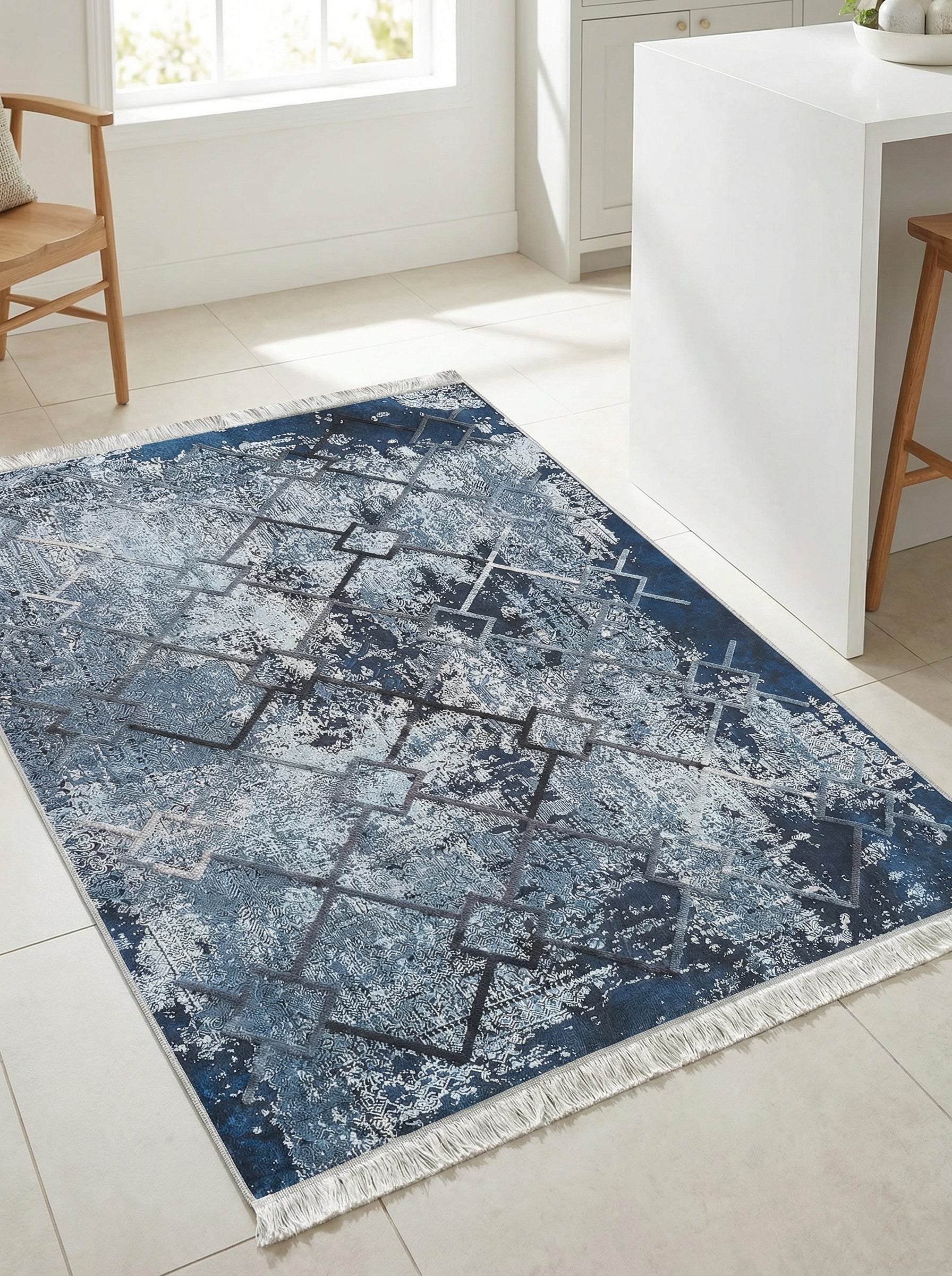 Tapis rectangulaire bleu marine et blanc aux motifs abstraits et géométriques gris, avec franges, posé sur un sol clair dans une pièce moderne