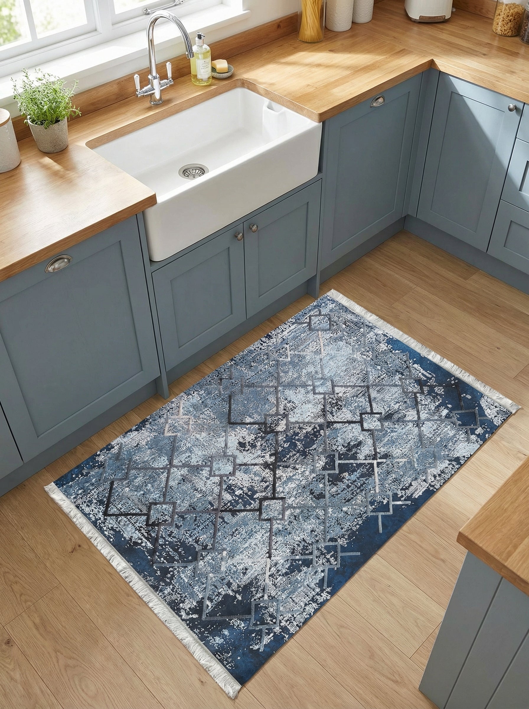 Tapis rectangulaire aux motifs abstraits et géométriques bleus, gris et blancs sur fond marine, posé dans une cuisine lumineuse