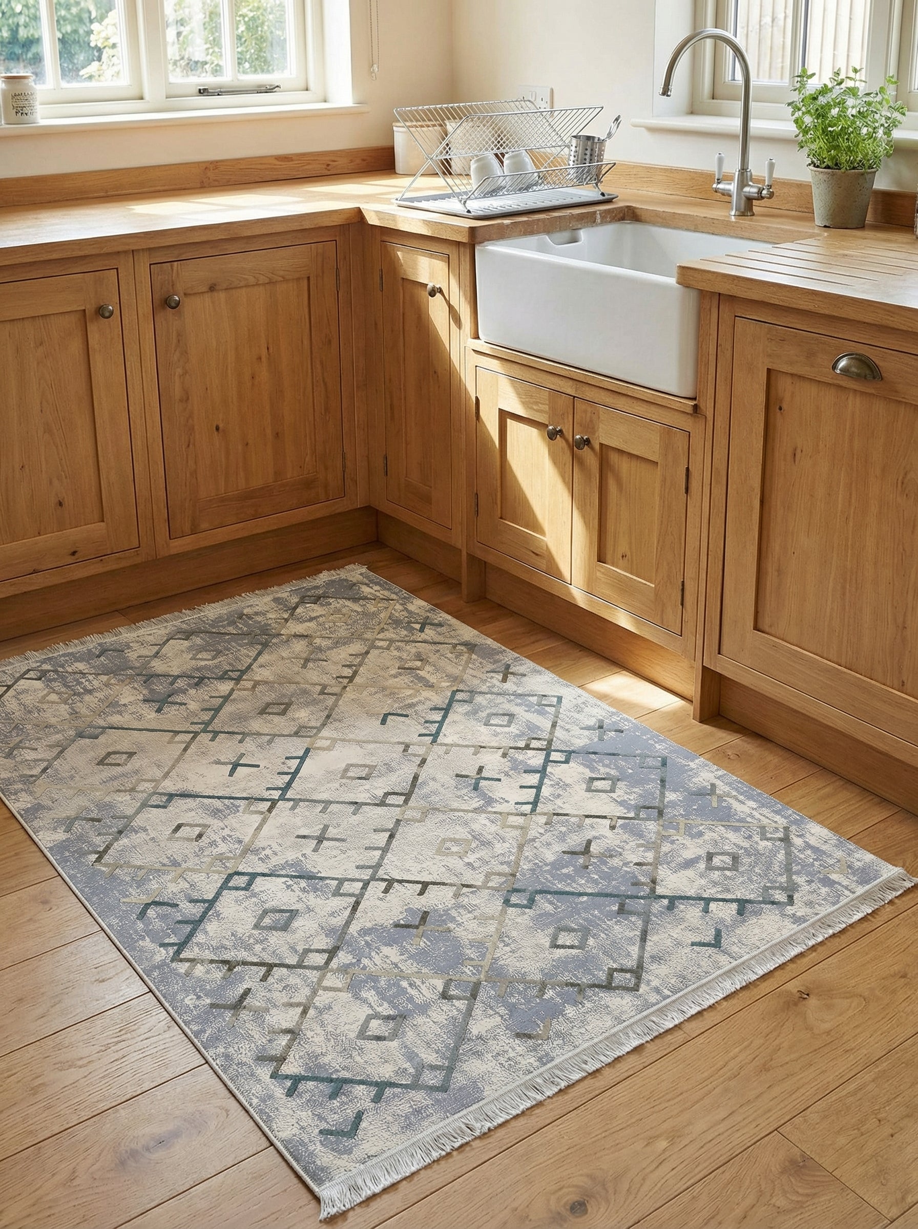 Tapis rectangulaire géométrique gris, bleu et beige, à l'aspect vieilli, avec franges, posé sur un parquet clair dans une cuisine