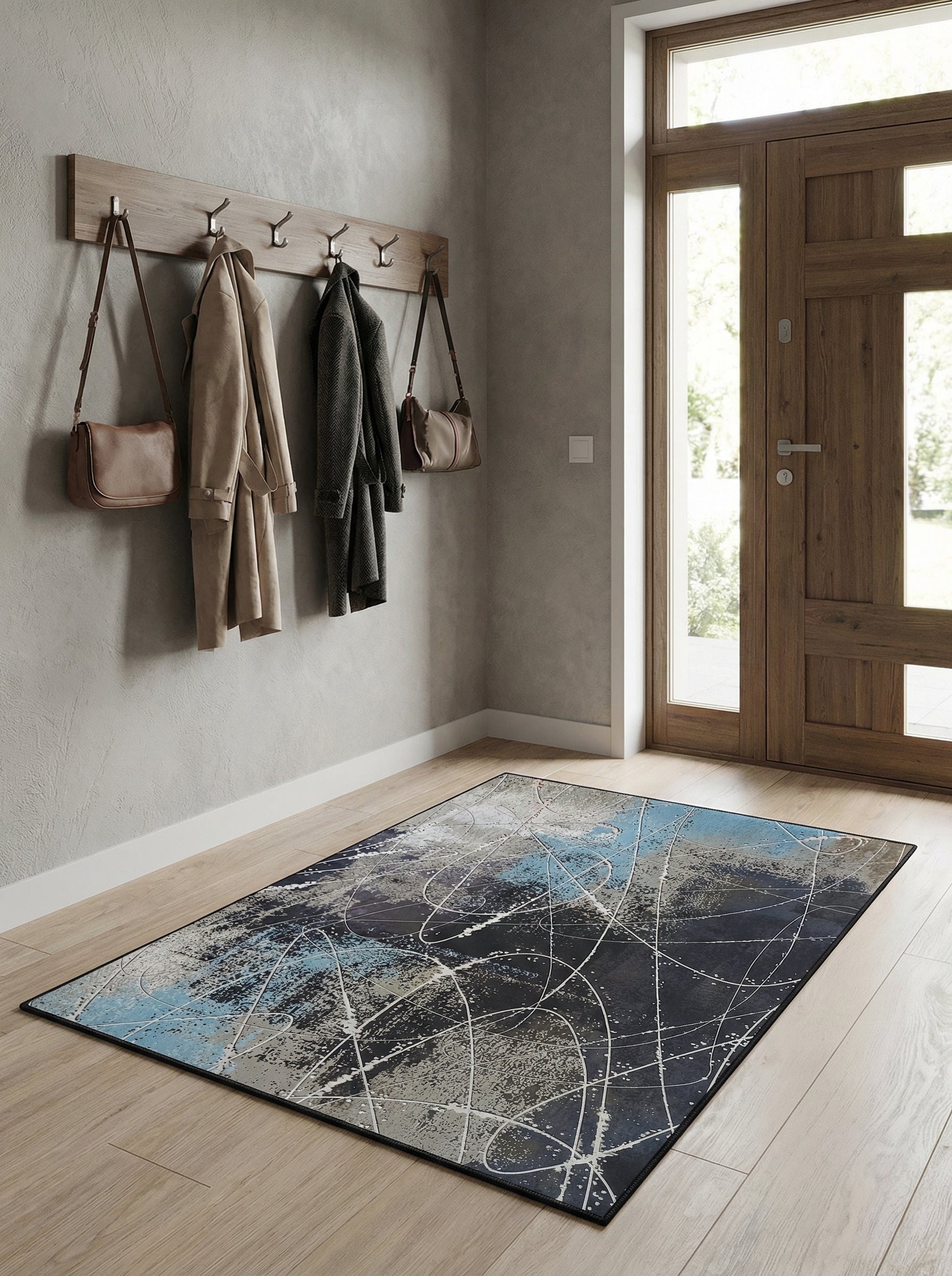 Tapis rectangulaire abstrait aux motifs d'éclaboussures et lignes blanches sur fonds gris, bleu et noir, posé dans une entrée