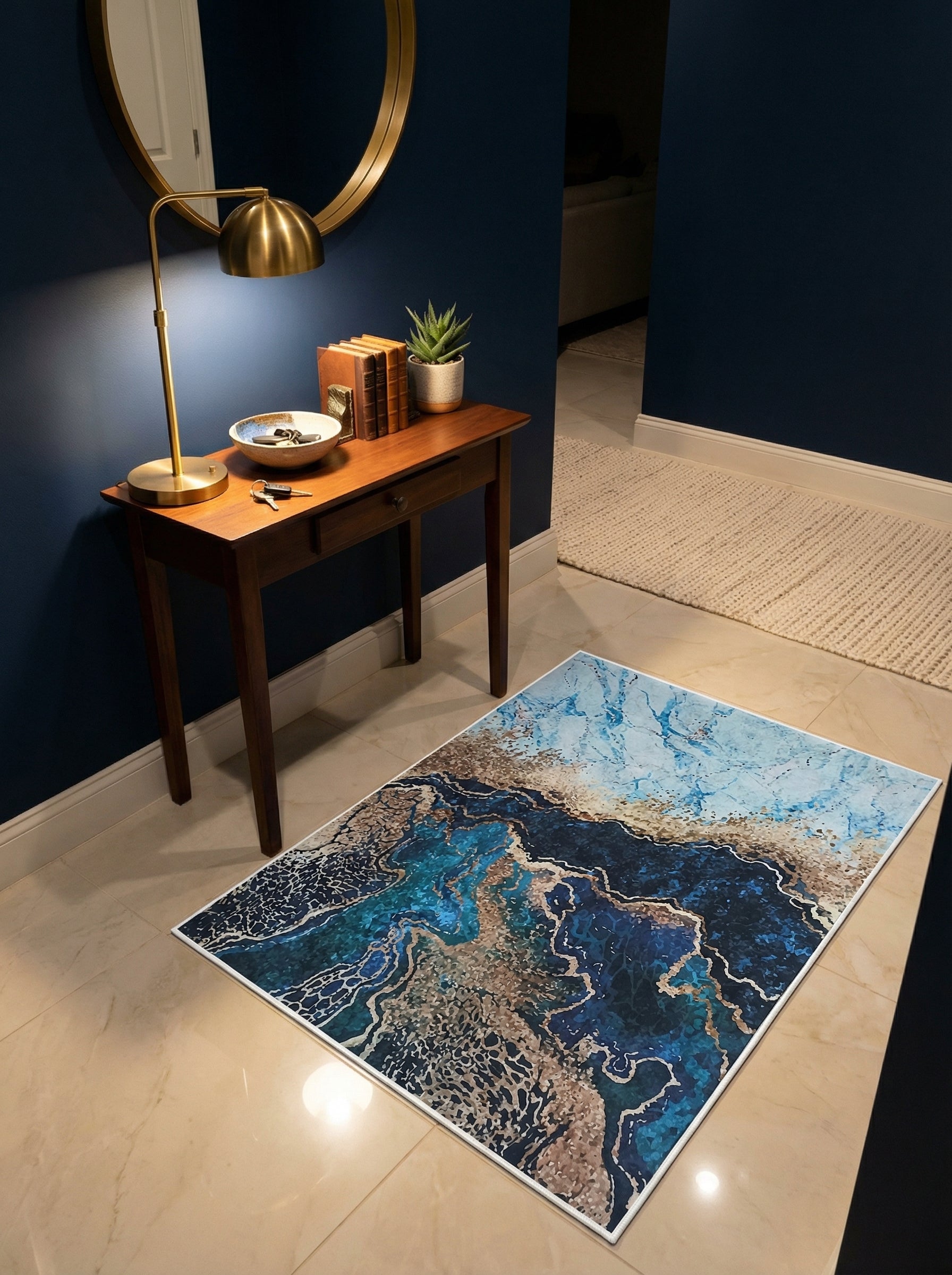 Tapis rectangulaire à motifs abstraits marbrés en bleus profonds, turquoise, blanc et touches dorées sur un sol carrelé beige dans une entrée