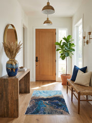 Tapis rectangulaire marbré bleu, turquoise et doré sur un parquet en bois clair dans une entrée lumineuse