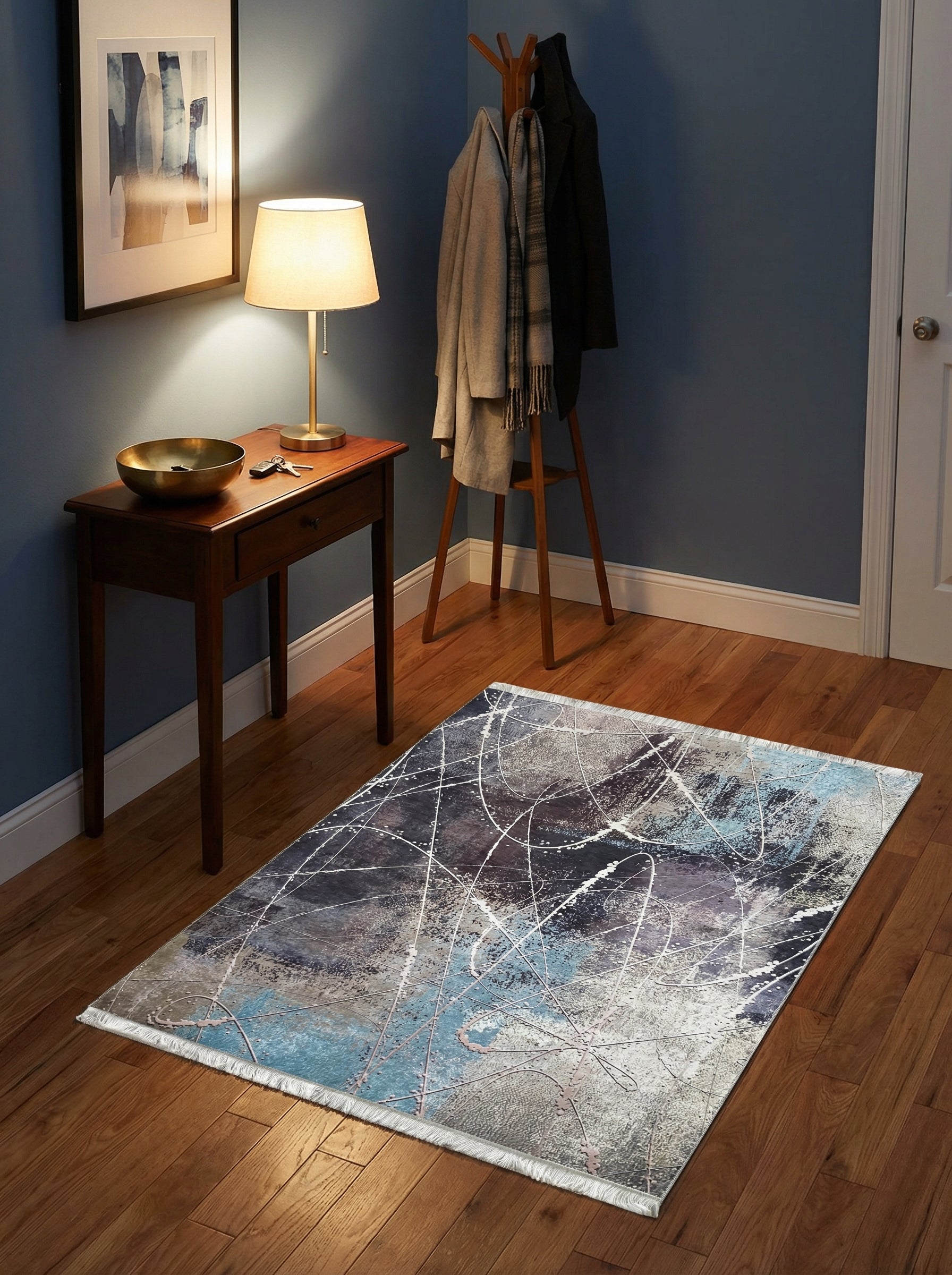 Tapis rectangulaire abstrait, motifs éclaboussés en bleu, gris, blanc et touches rouille, franges blanches, sur parquet d'une entrée