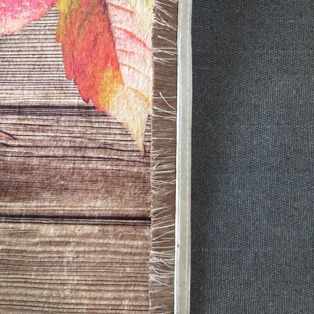 Tapis montrant sa face imprimée bois et feuilles d'automne rouges et son envers gris texturé, avec un bord blanc cousu