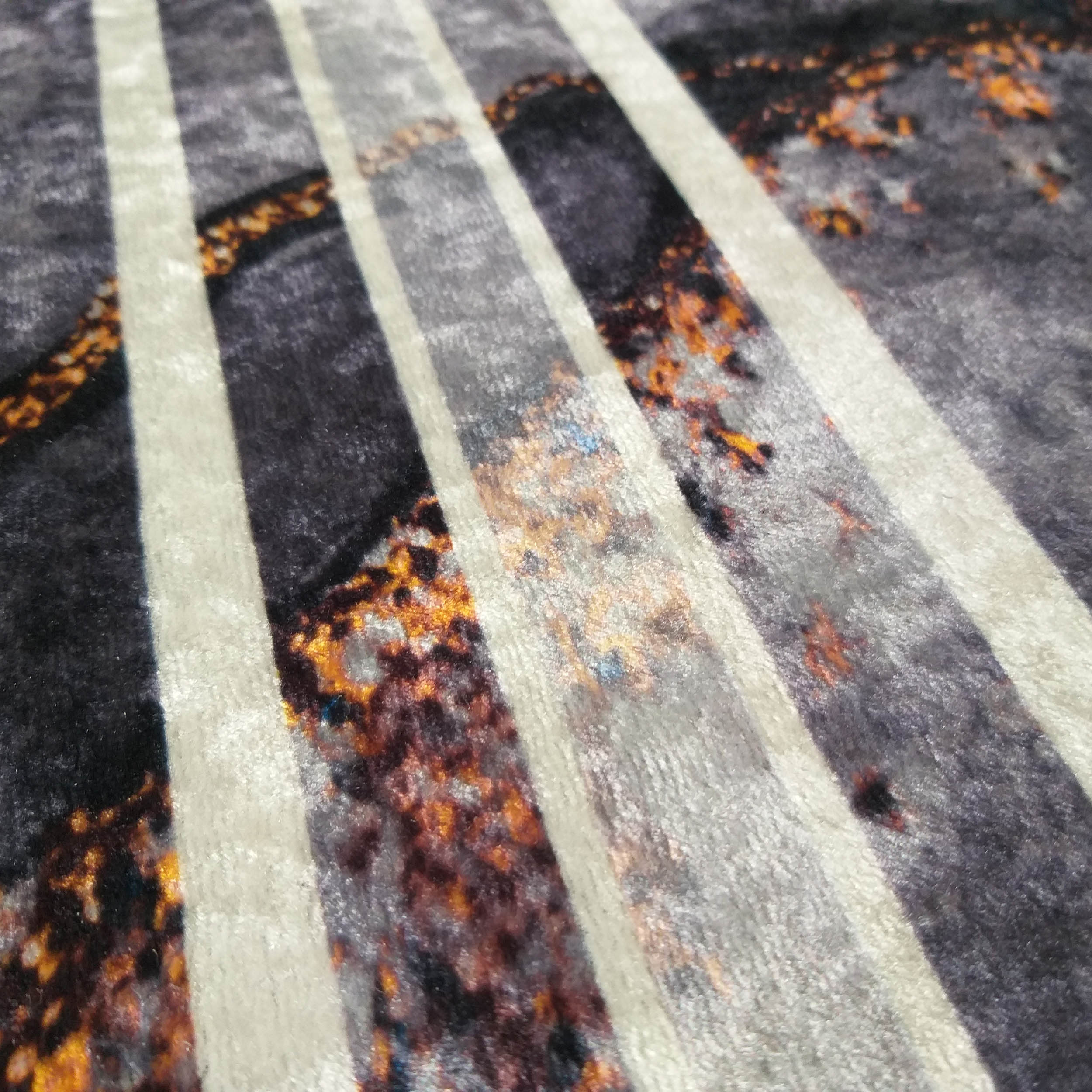 Tapis doux à rayures parallèles beige clair sur un fond texturé gris foncé, moucheté d'orange, marron et bleu