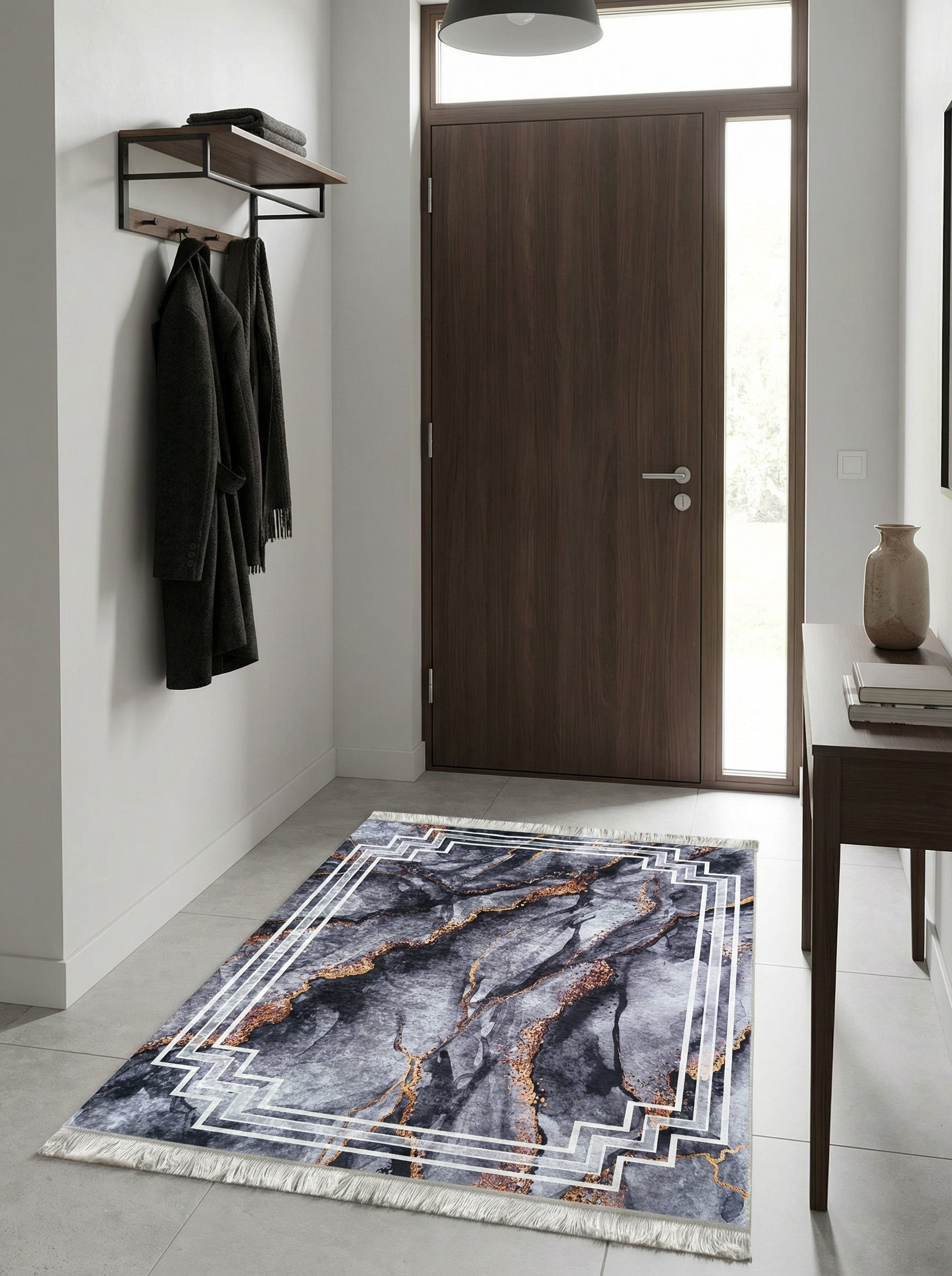 Tapis rectangulaire gris anthracite aux motifs marbrés dorés et bordure géométrique blanche, avec franges, dans une entrée