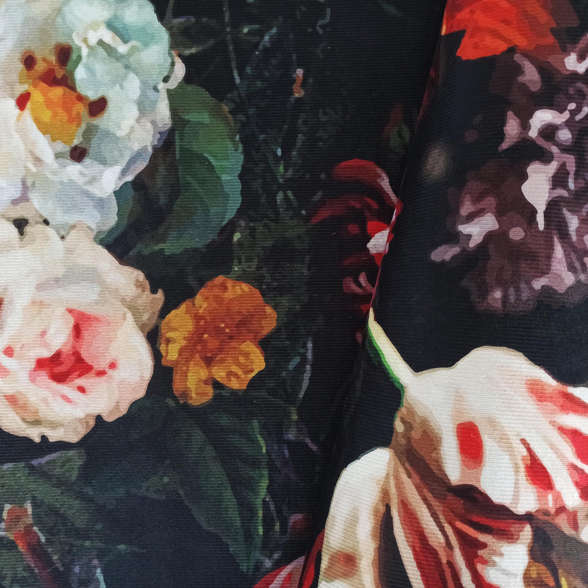 Tapis avec des fleurs peintes blanches, rouges et orange sur un fond noir ou très foncé, montrant sa texture tissée