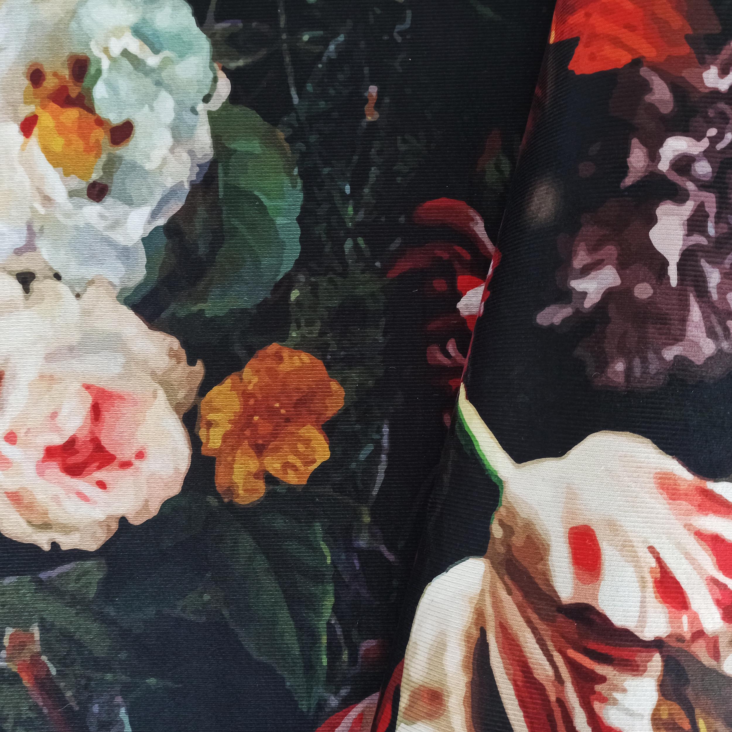 Tapis avec des fleurs peintes blanches, rouges et orange sur un fond noir ou très foncé, montrant sa texture tissée