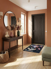 Tapis rectangulaire en tissu, à motif floral dense sur fond sombre, présentant des fleurs variées aux couleurs éclatantes, dans une entrée au sol parqueté