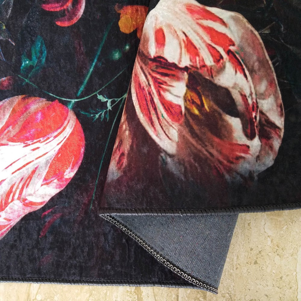 Tapis à motifs floraux sombres aux tulipes rouges et blanches, sa surface veloutée est repliée sur un revers gris