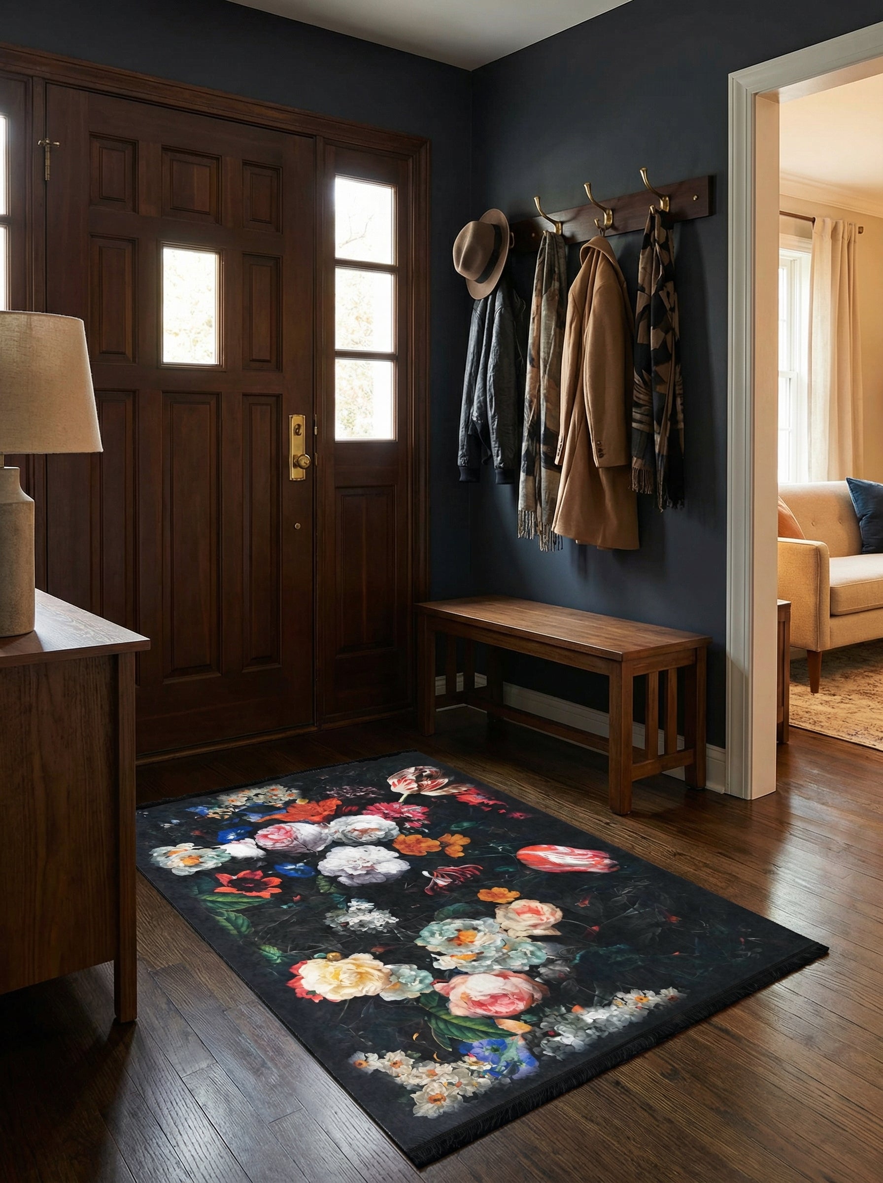 Tapis rectangulaire noir orné d'un riche motif floral aux couleurs vives (blanc, rose, rouge, bleu) dans une entrée au sol en bois
