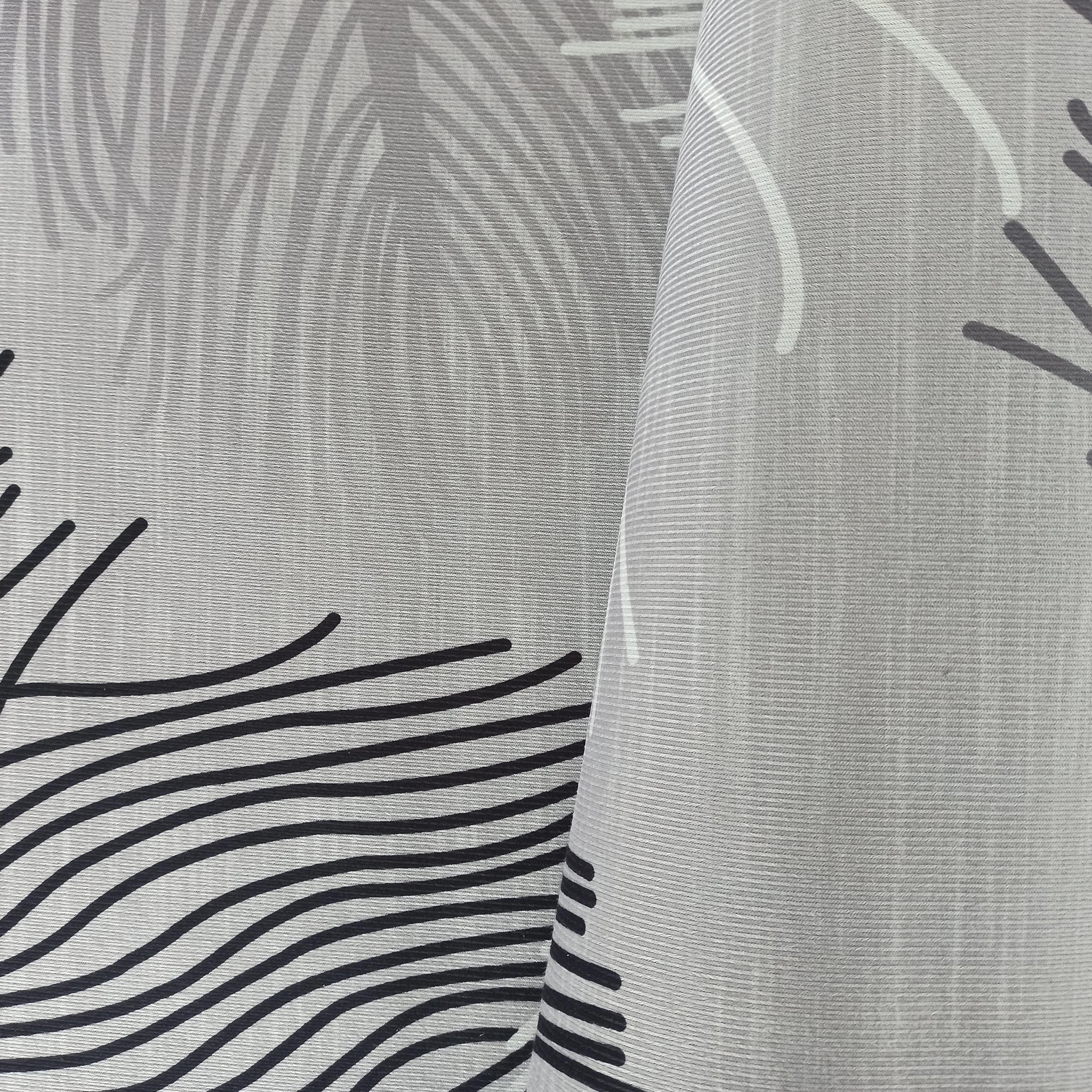 Tapis gris clair à texture striée avec des motifs de feuilles gris pâle et de lignes ondulées noires, une section est repliée