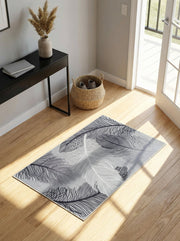 Tapis rectangulaire gris à motifs de plumes blanches et noires sur un parquet clair dans une entrée ensoleillée