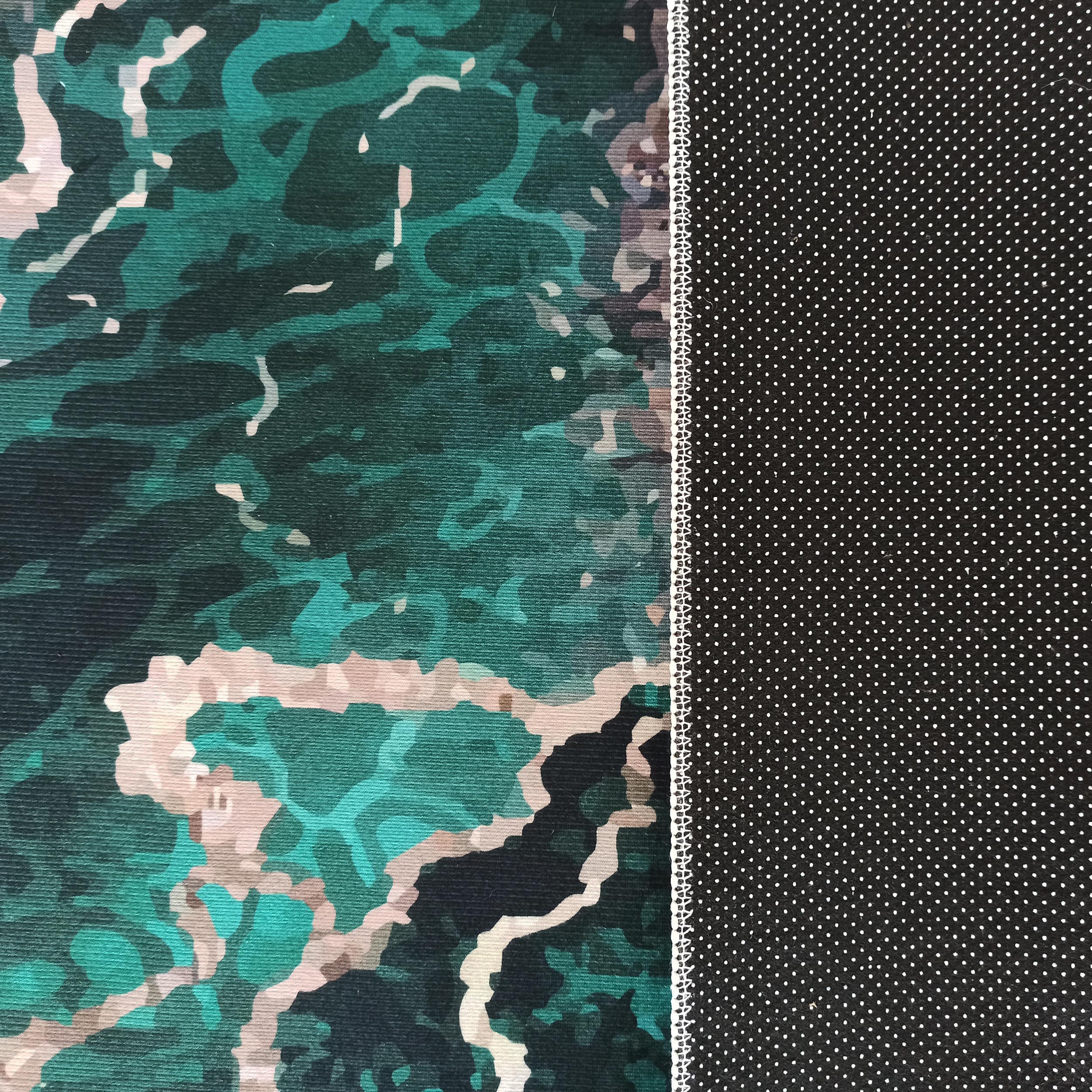 Tapis présentant une surface texturée à motifs abstraits vert émeraude et beige, avec un revers noir à petits pois blancs séparé par une couture