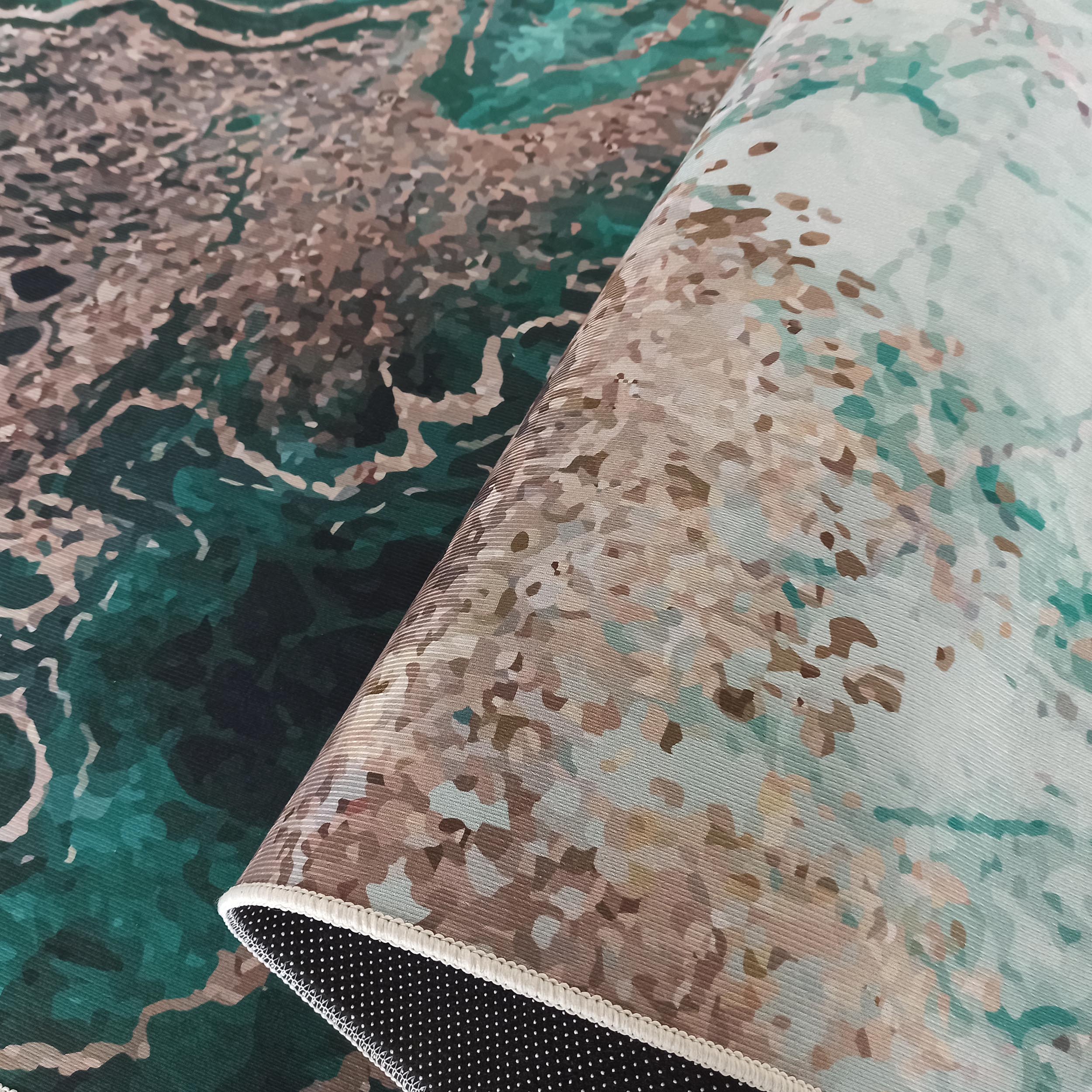 Tapis enroulé avec un motif abstrait marbré vert émeraude et marron, montrant son envers clair et sa doublure noire à pois