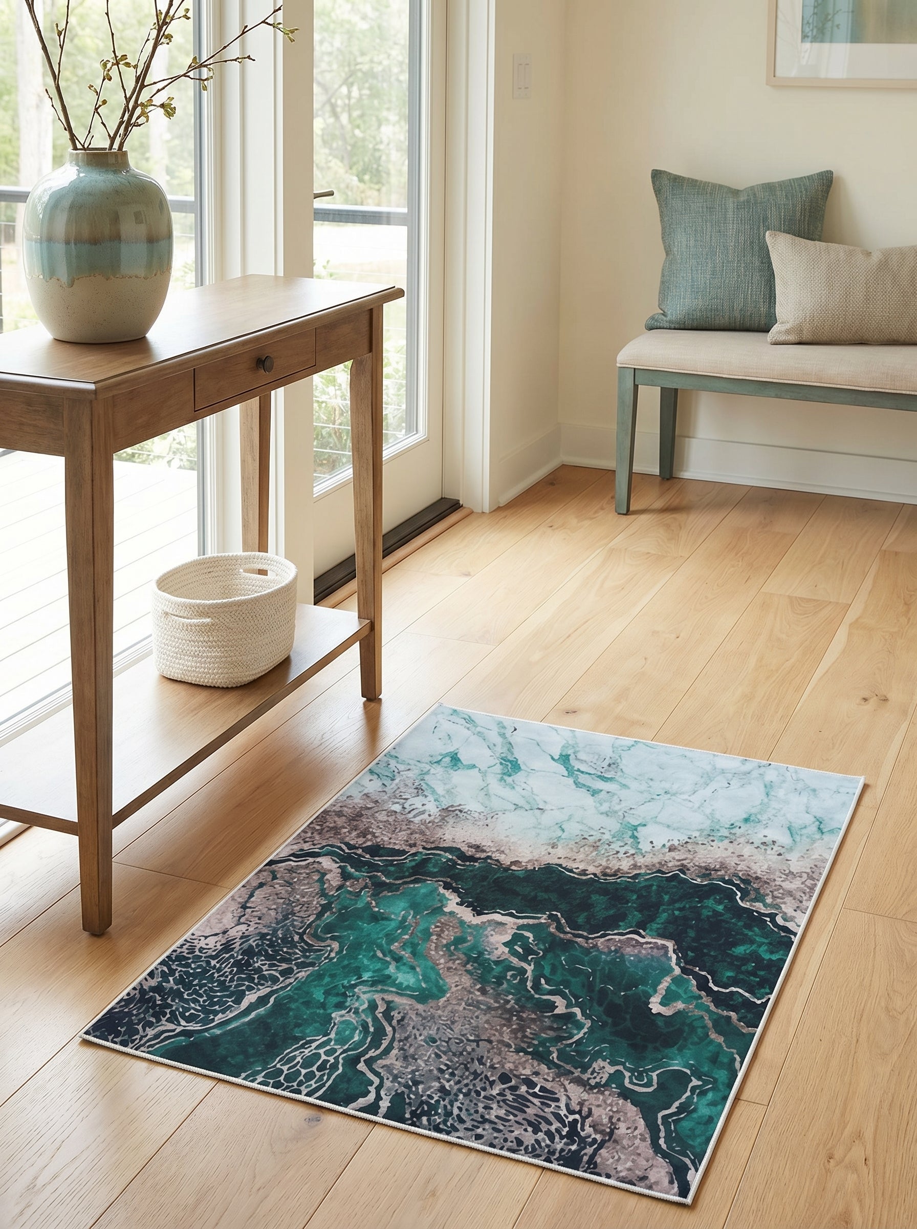 Tapis rectangulaire aux motifs abstraits marbrés vert émeraude, bleu clair et gris métallisé, sur un plancher en bois clair dans une entrée