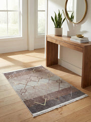 Tapis rectangulaire à motifs géométriques de carrés et lignes, en dégradé de gris, brun et touches dorées, sur un parquet clair dans une entrée