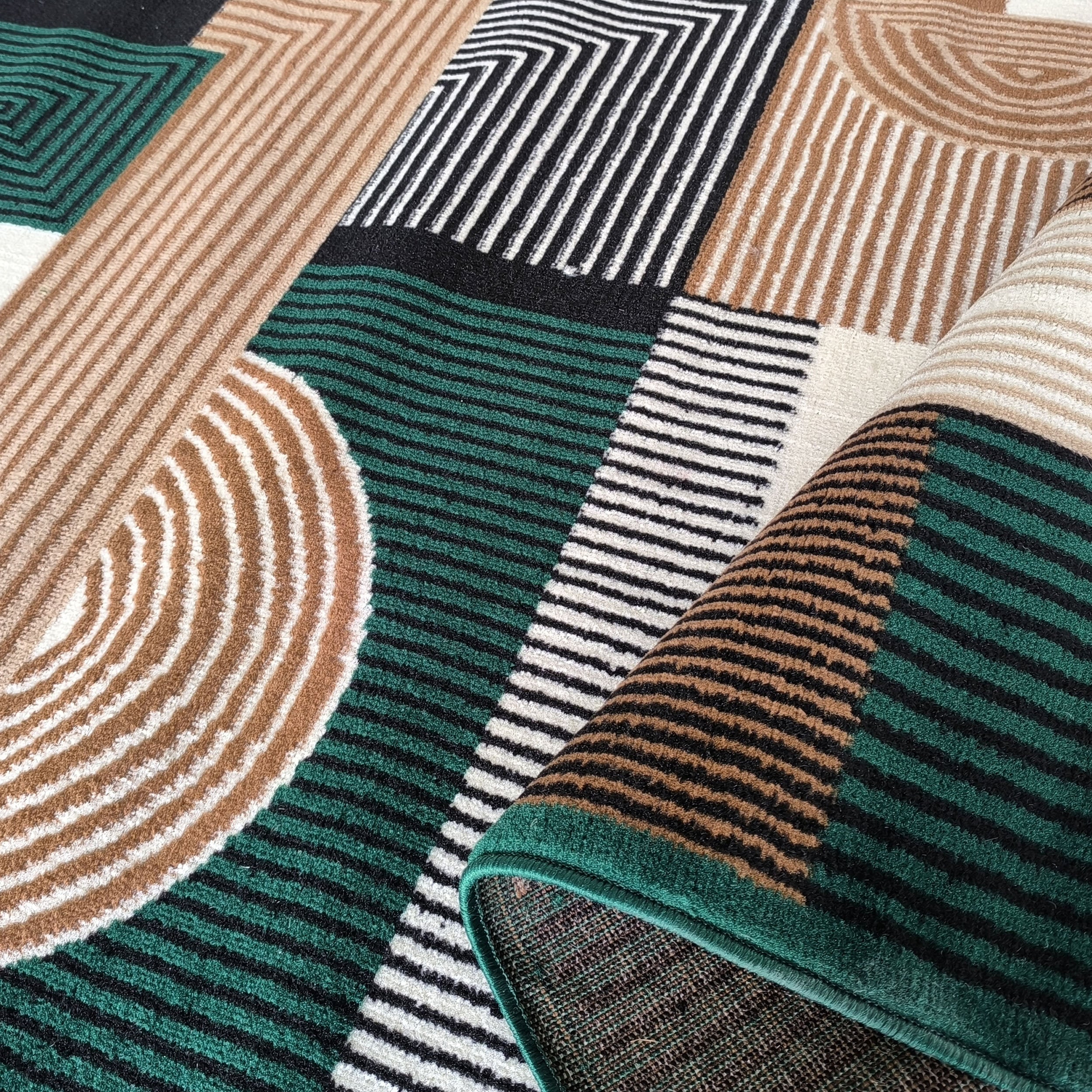 Tapis coloré partiellement roulé, aux motifs géométriques et rayures en vert canard, noir, beige et blanc crème