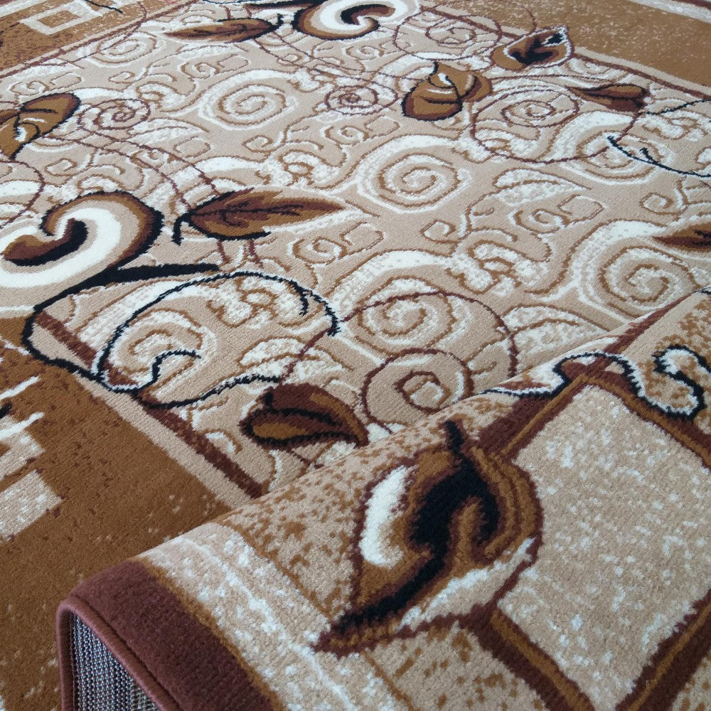 Tapis beige et marron clair avec des motifs floraux et arabesques en marron foncé, blanc et noir. Le tapis est partiellement enroulé