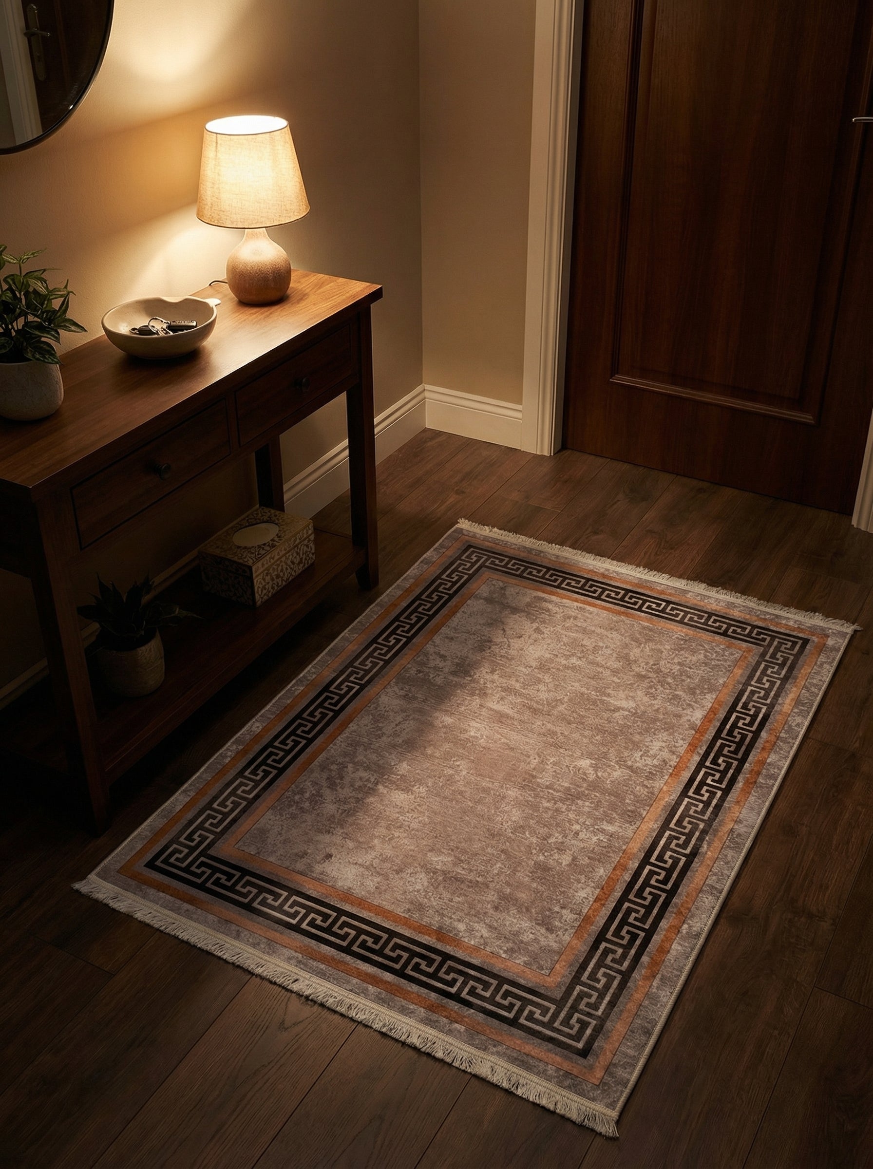 Tapis rectangulaire beige à l'aspect vieilli, bordure marron avec motif grec noir, franges claires, dans une entrée