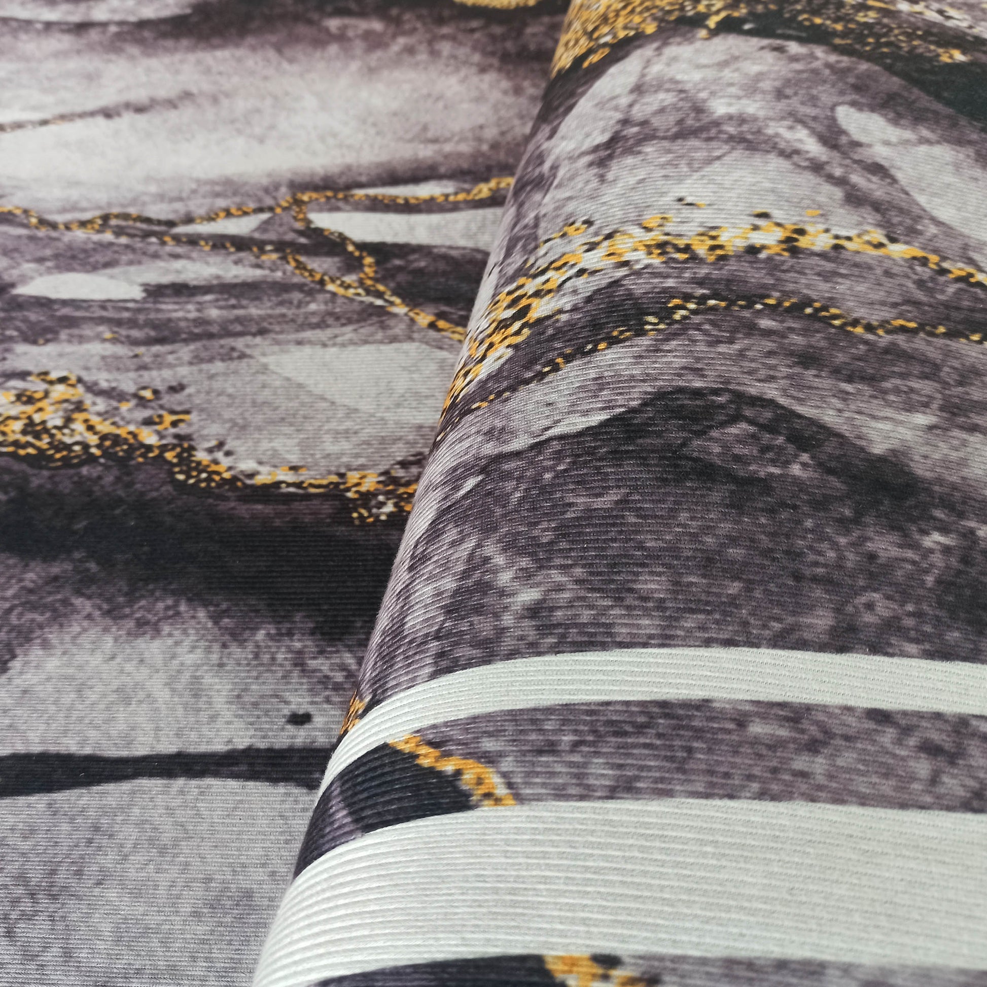 Tapis roulé aux motifs abstraits gris clair à foncé, marbrés de blanc et parsemés de veines dorées scintillantes