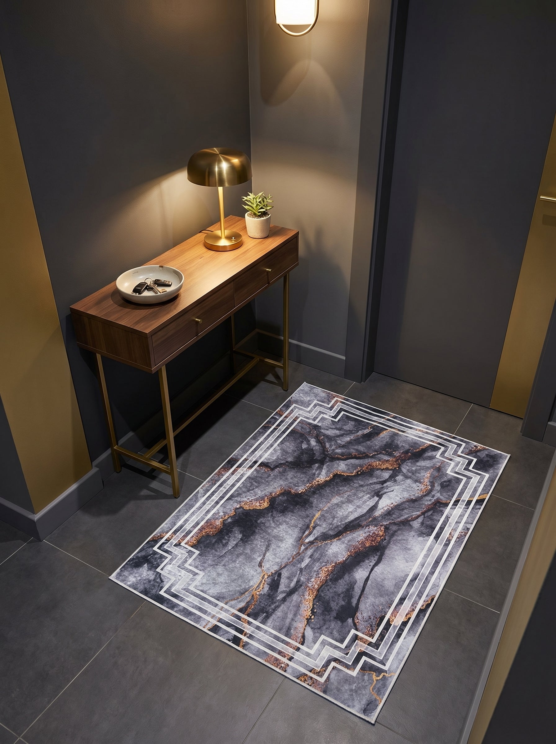 Tapis rectangulaire gris et noir effet marbre aux veines dorées, bordé d'un motif géométrique blanc, dans une entrée