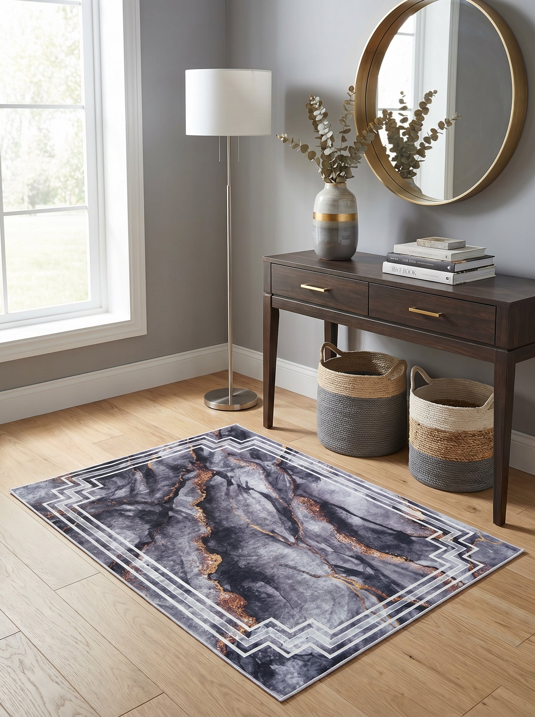 Tapis rectangulaire gris foncé marbré de doré avec une bordure géométrique blanche, posé sur un parquet clair dans une entrée moderne