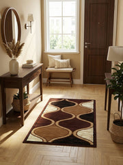 Tapis rectangulaire moelleux aux motifs ondulés abstraits marron foncé, camel et beige crème, bordés de doré, sur parquet clair dans une entrée