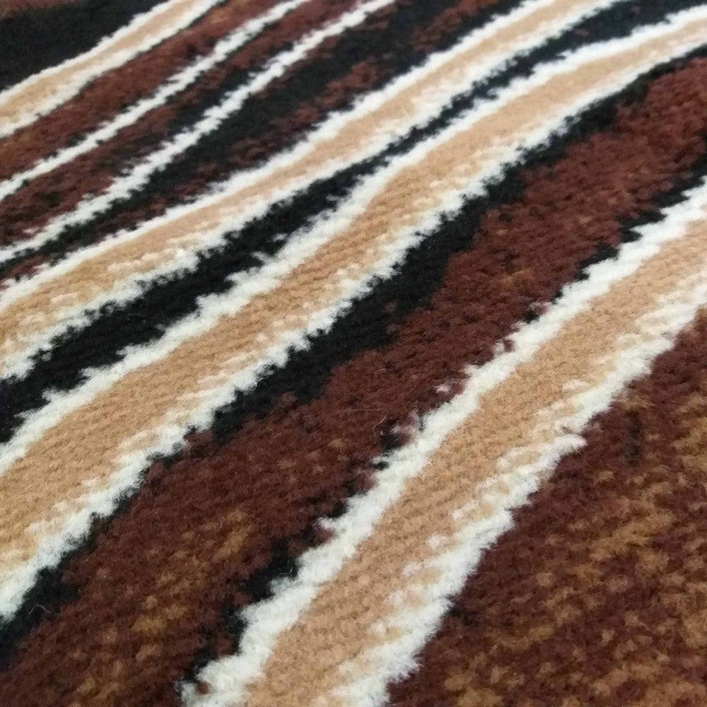 Tapis à texture fibreuse douce avec un motif de larges rayures diagonales irrégulières, aux couleurs marron, beige, noir et blanc