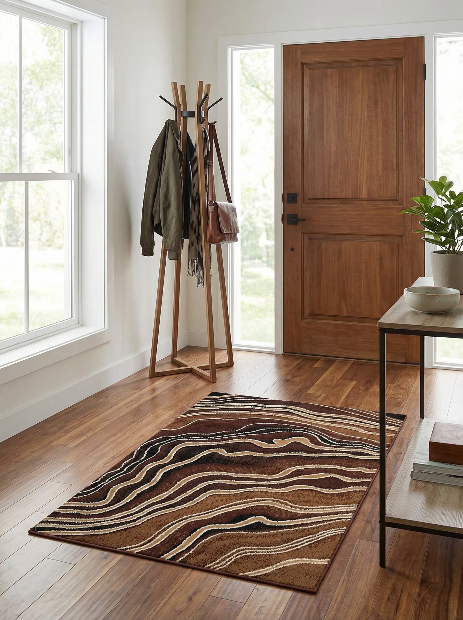 Tapis rectangulaire aux motifs abstraits ondulés marron foncé, marron clair, beige, noir et blanc, posé sur un parquet en bois dans une entrée lumineuse