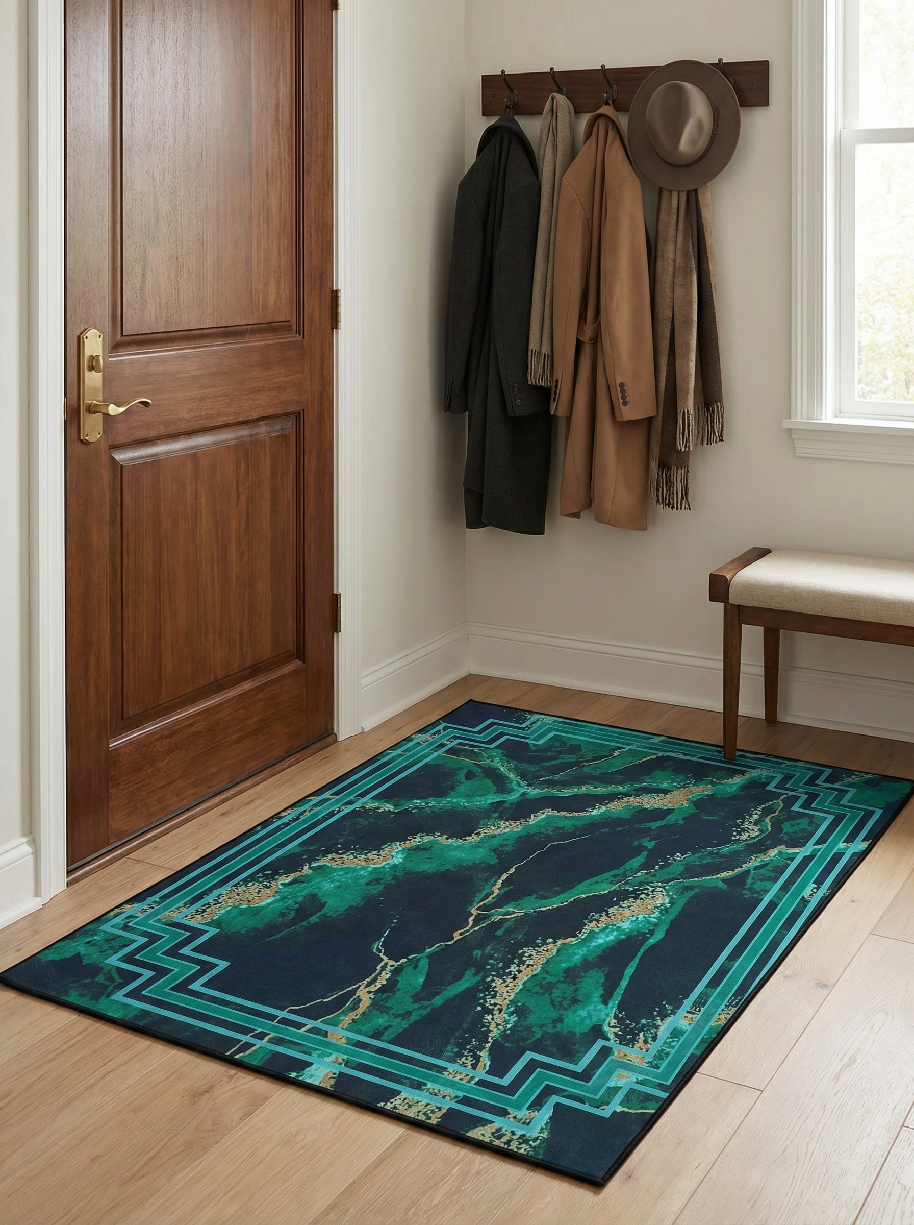 Tapis bleu marine et vert émeraude marbré de doré, avec une bordure géométrique turquoise, posé sur un parquet clair dans une entrée