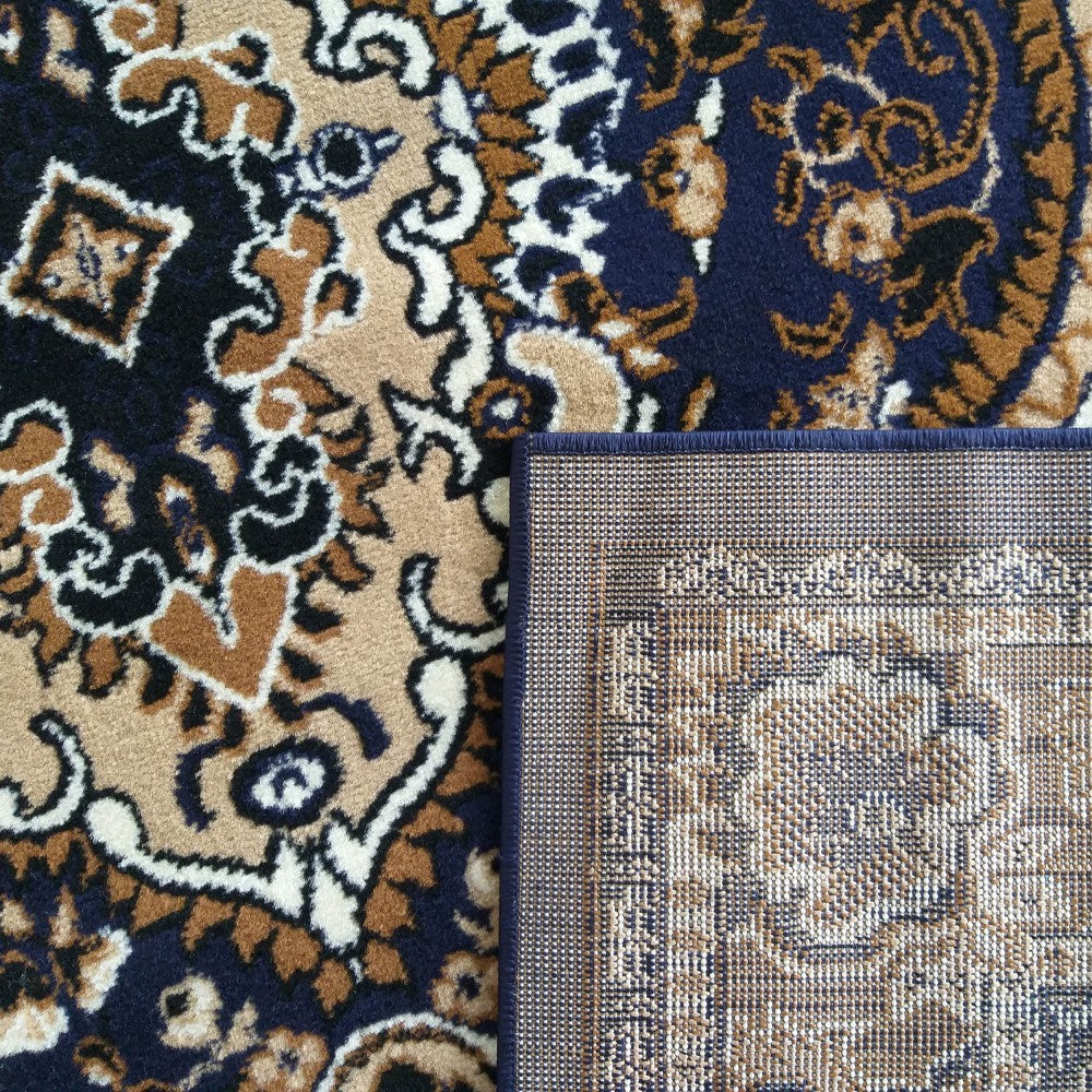Tapis aux motifs traditionnels en bleu marine, beige, marron et blanc crème, dont un coin est relevé montrant l'envers tissé
