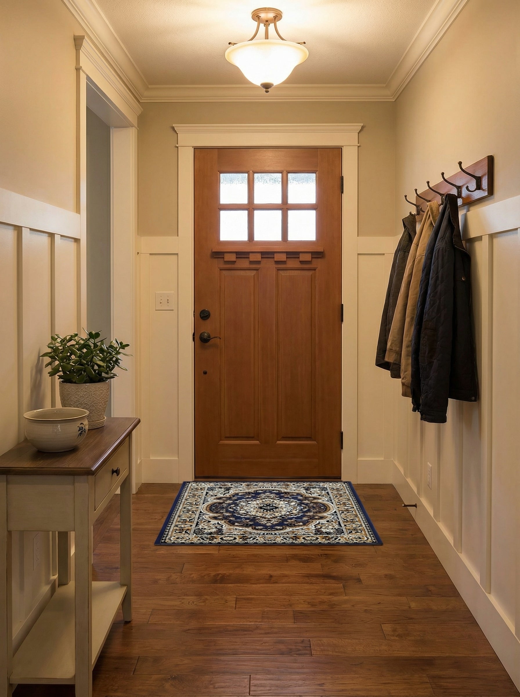 Tapis rectangulaire à motifs floraux et arabesques bleu foncé, crème et doré devant une porte en bois dans une entrée