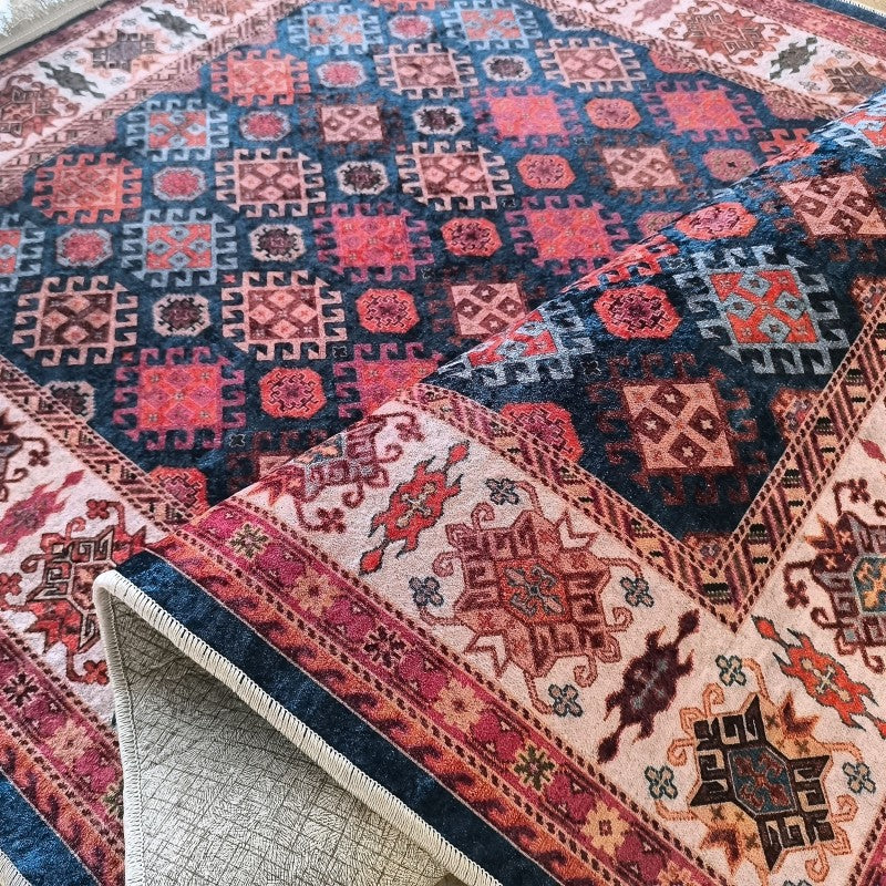 Tapis en velours à motifs géométriques complexes rouges, bleus et beiges. Une partie du tapis est soulevée, montrant son envers texturé