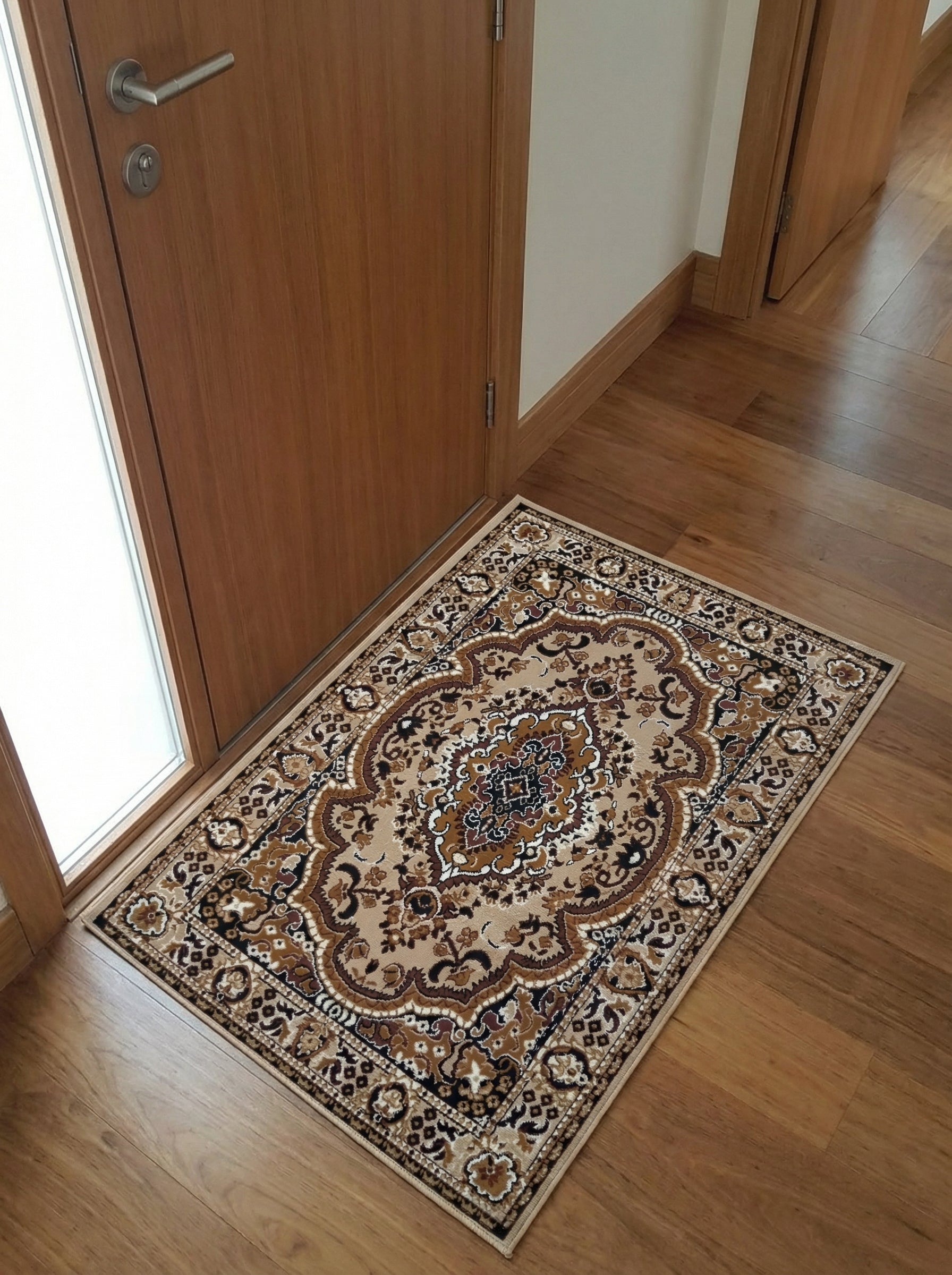 Tapis rectangulaire beige aux motifs floraux et arabesques marron, noirs et crème, sur un parquet en bois dans une entrée