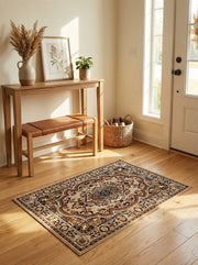 Tapis rectangulaire beige à motifs ornementaux marron, noirs et bleus, avec un médaillon central, sur parquet clair dans une entrée ensoleillée