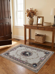 Tapis rectangulaire beige clair orné de volutes baroques et médaillons floraux colorés, avec une bordure marron, dans une entrée
