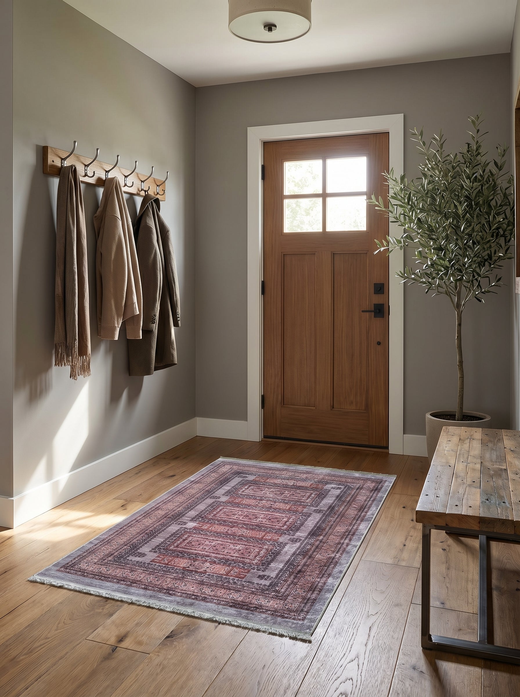 Tapis rectangulaire aux motifs orientaux rouges et gris effet vieilli, avec franges, posé sur un parquet en bois dans une entrée