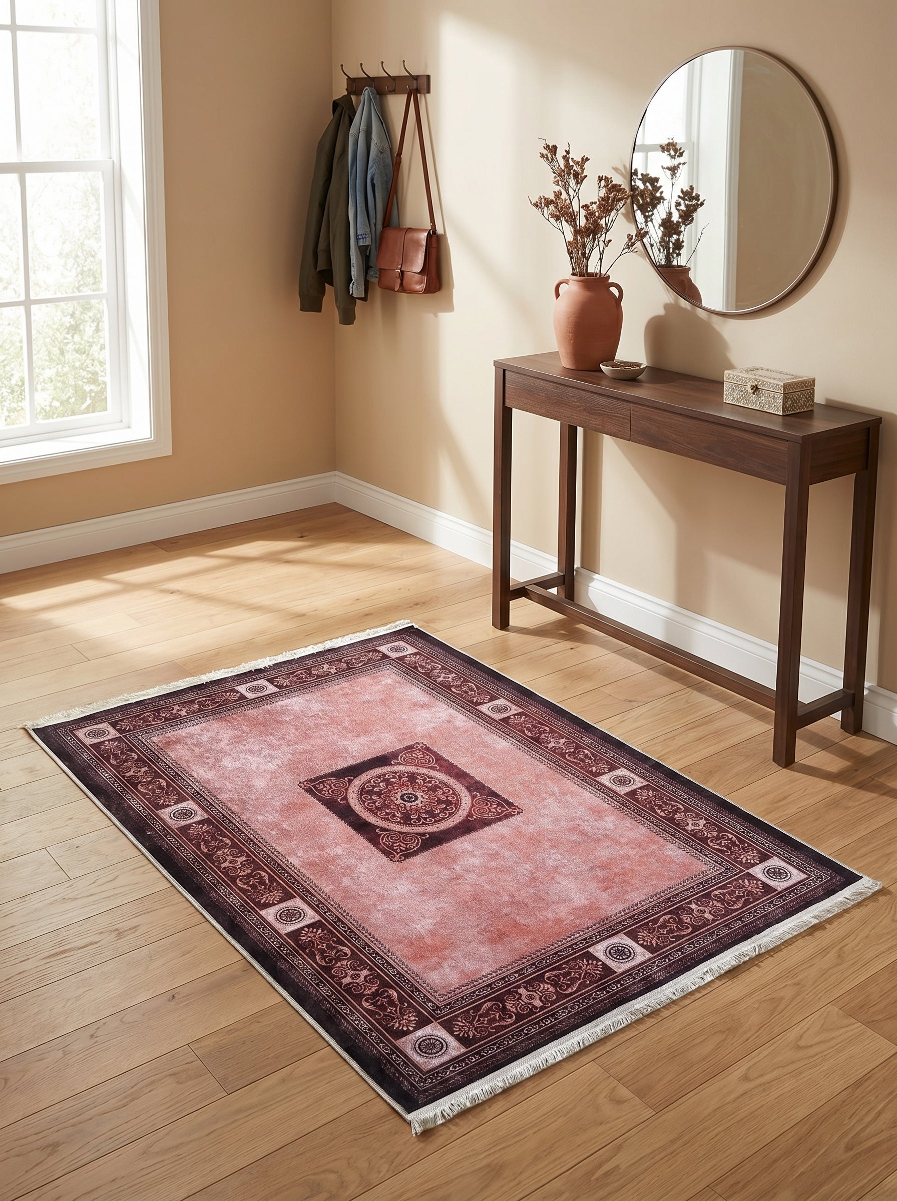 Tapis rectangulaire d'inspiration persane rose pâle avec motifs centraux et bordures bordeaux foncé et franges, posé sur un parquet clair dans un hall d'entrée
