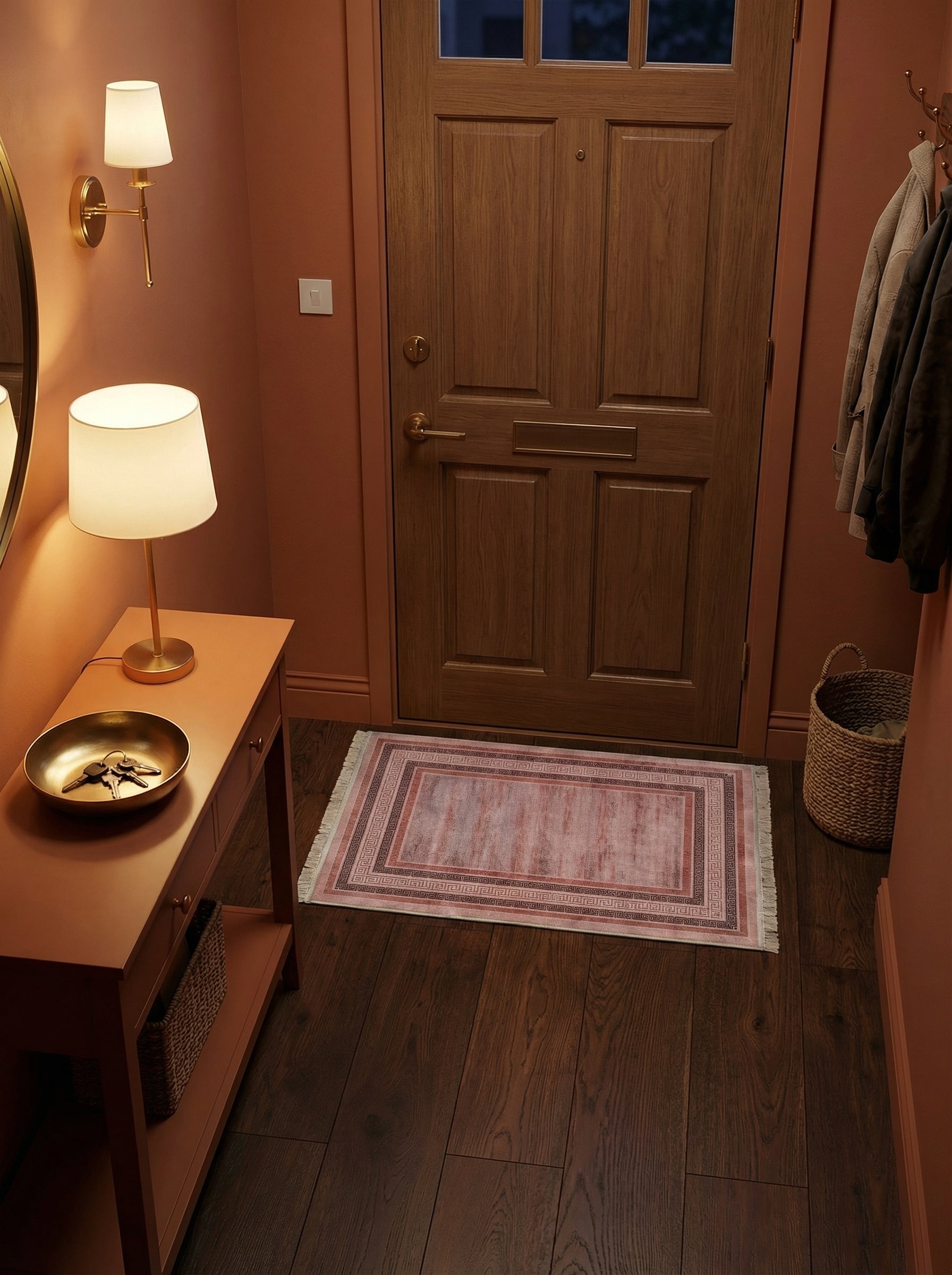 Tapis rectangulaire à franges, au centre rose vieilli avec motifs géométriques méandre roses et marron sur les bordures, dans une entrée