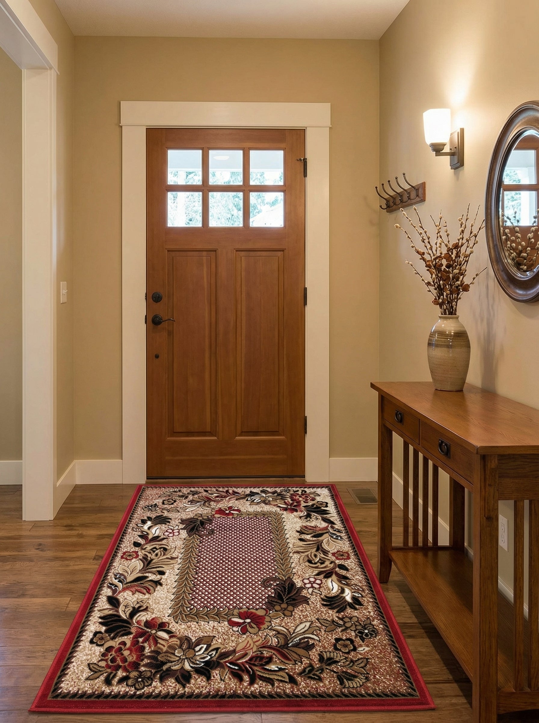 Tapis rectangulaire beige aux motifs floraux rouges, noirs et marron, bordure rouge intense, sur parquet en bois dans une entrée