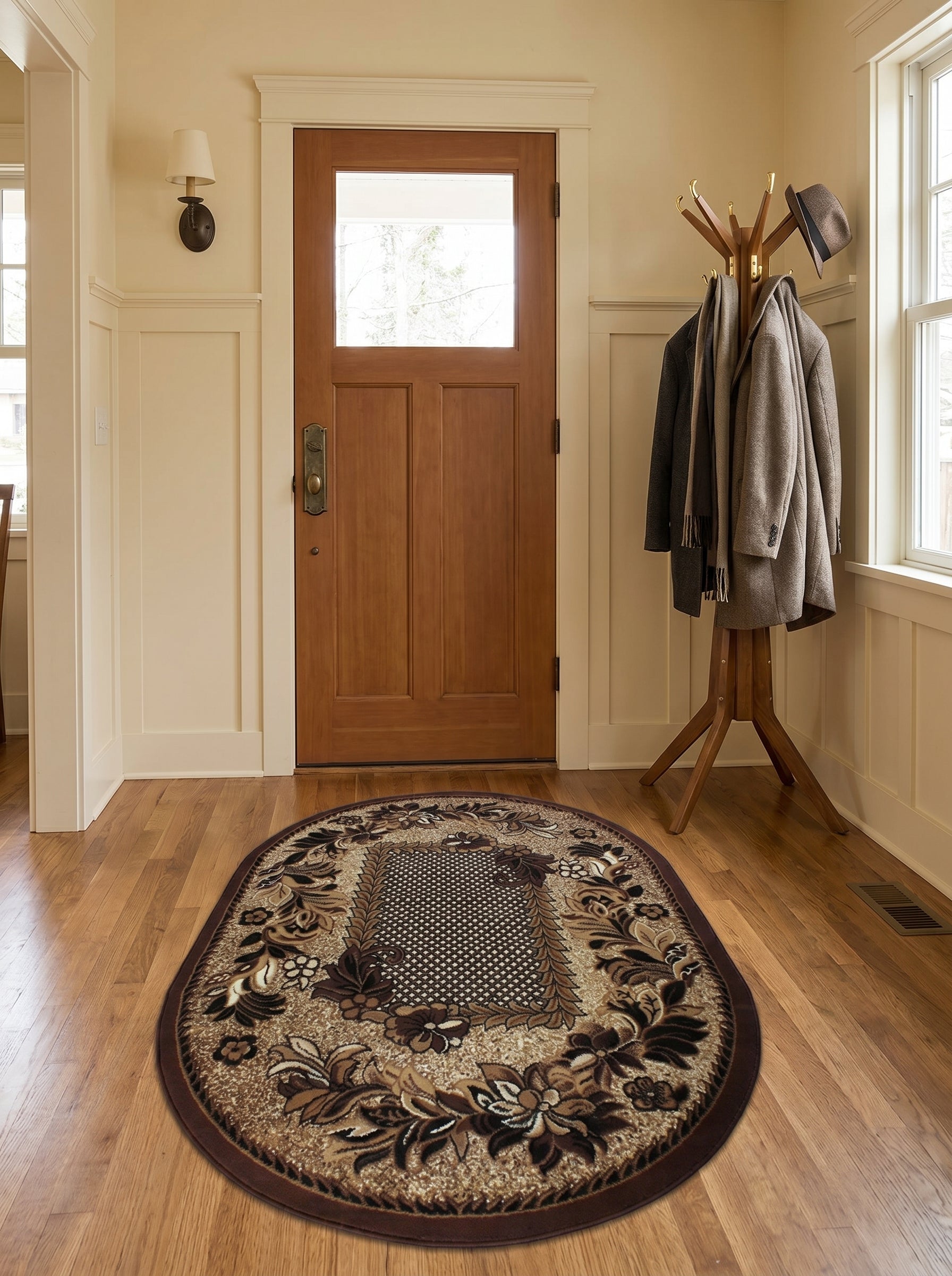 Tapis ovale marron et beige aux motifs floraux détaillés et quadrillé central, sur un plancher d'entrée