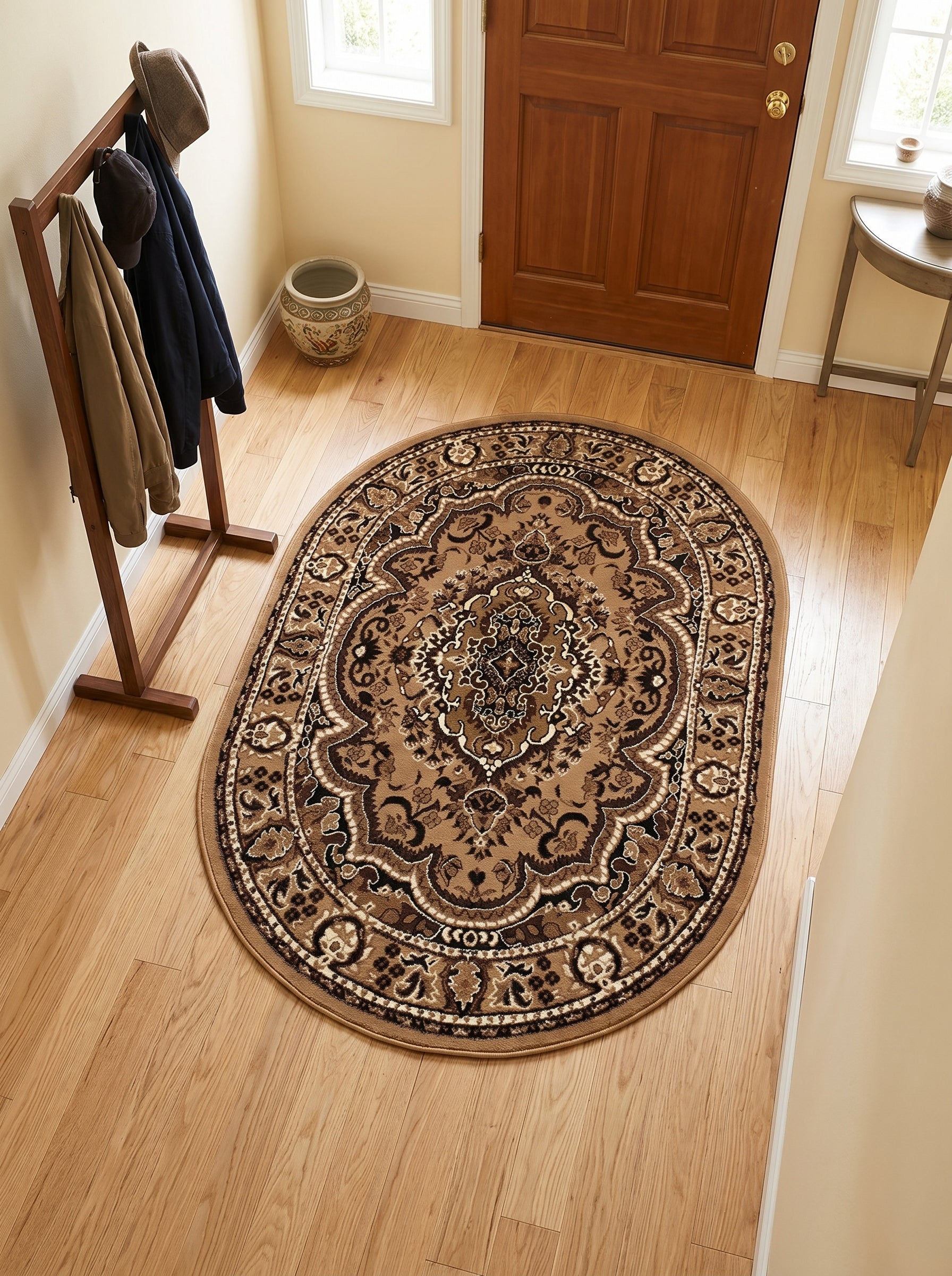 Tapis ovale aux motifs ornementaux classiques beiges, marron et crème sur plancher en bois clair d'une entrée