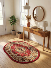 Tapis ovale rouge profond avec des motifs floraux et géométriques beiges, or et noirs, sur un parquet dans une entrée lumineuse