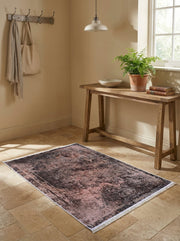 Tapis rectangulaire aux motifs orientaux délavés, nuances de noir, rose et gris, avec franges blanches, sur carrelage beige d'une entrée